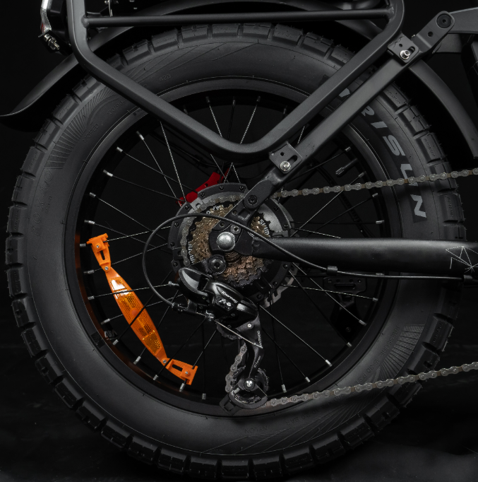 Das Hinterrad eines schwarzen Fahrrads mit Kette, Schaltung und orangem Reflektor.