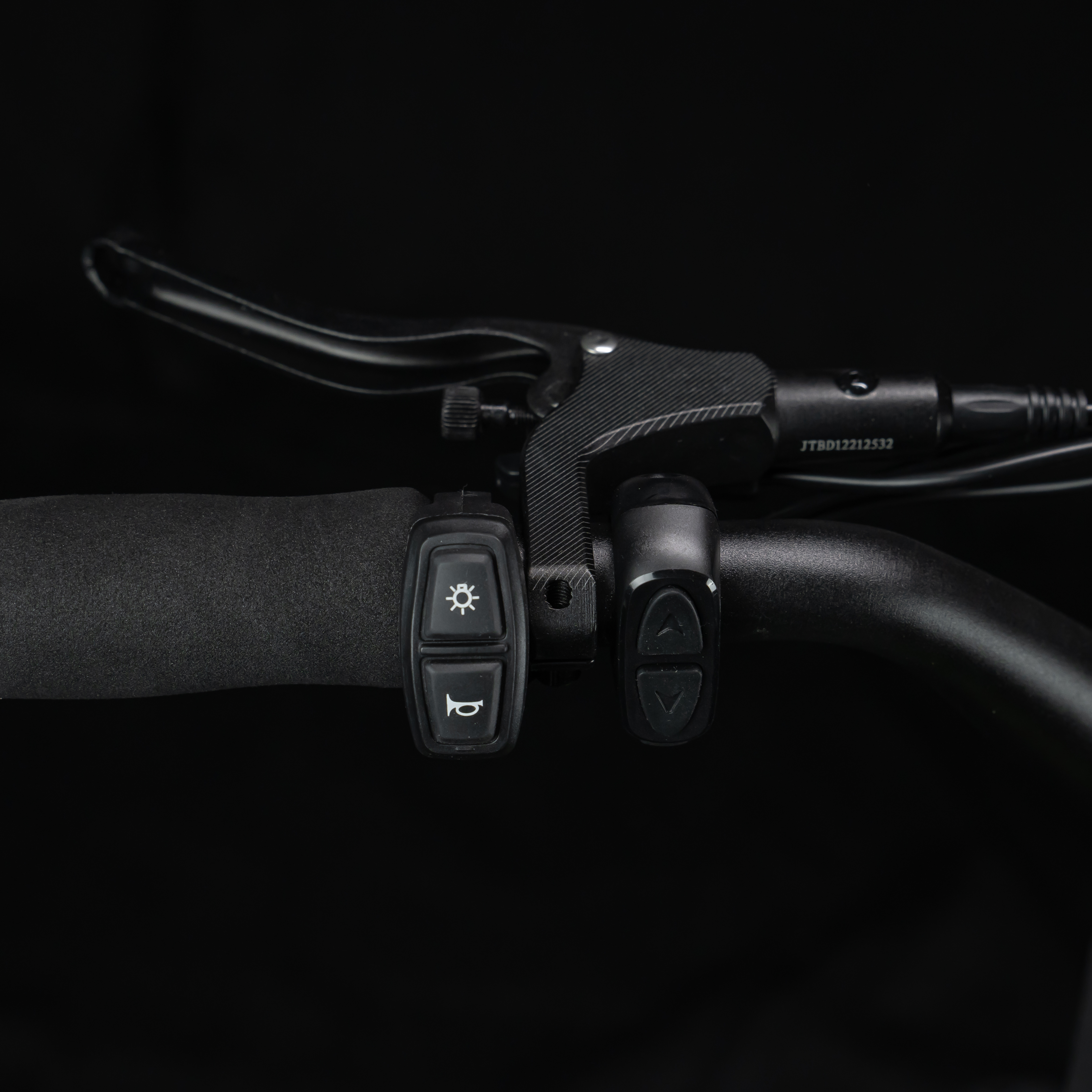 Nahaufnahme des Lenkers eines E-Bikes mit Bedienelementen für Licht und Hupe.