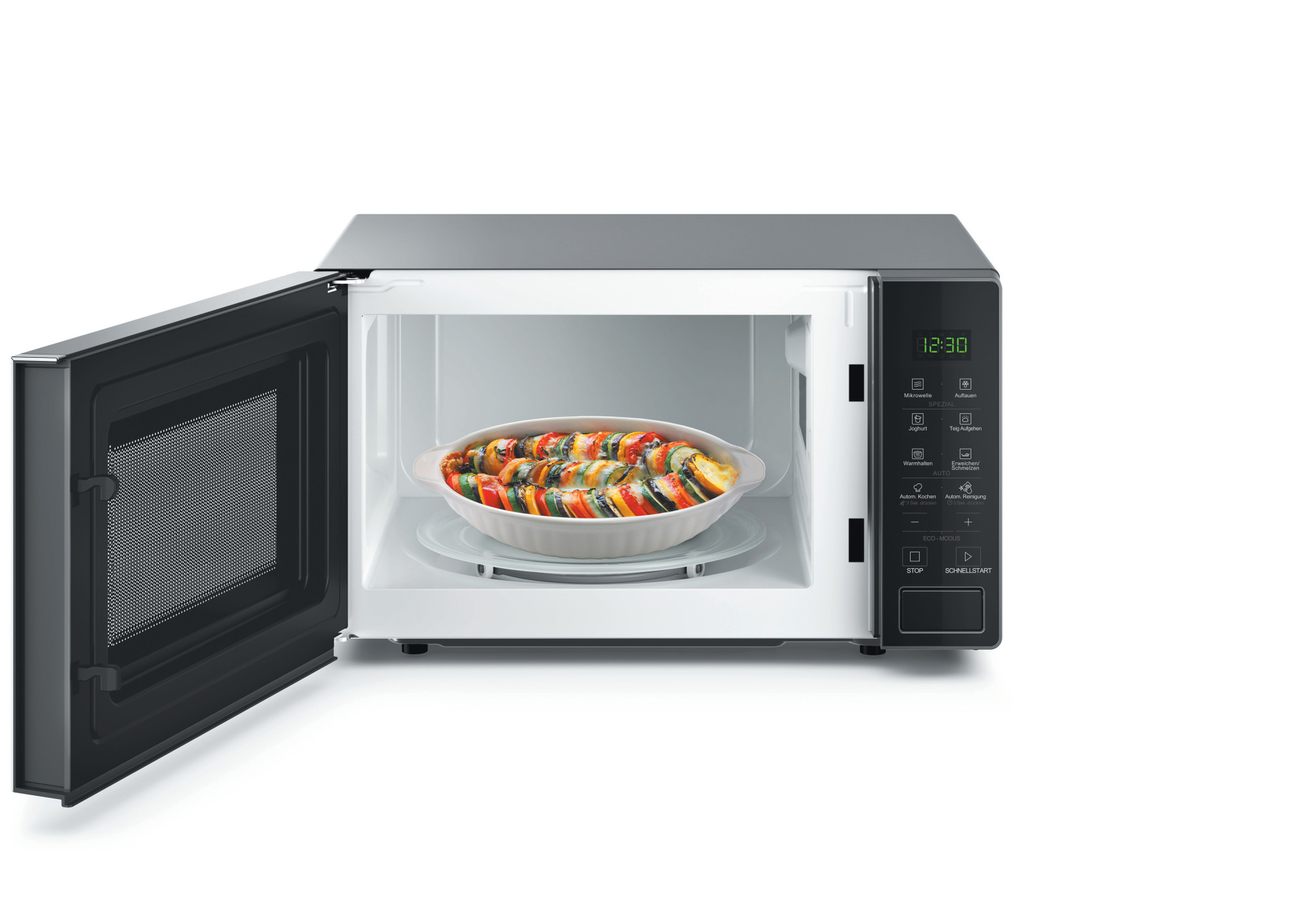 Offene Mikrowelle mit einer Auflaufform mit Ratatouille auf dem Drehteller.