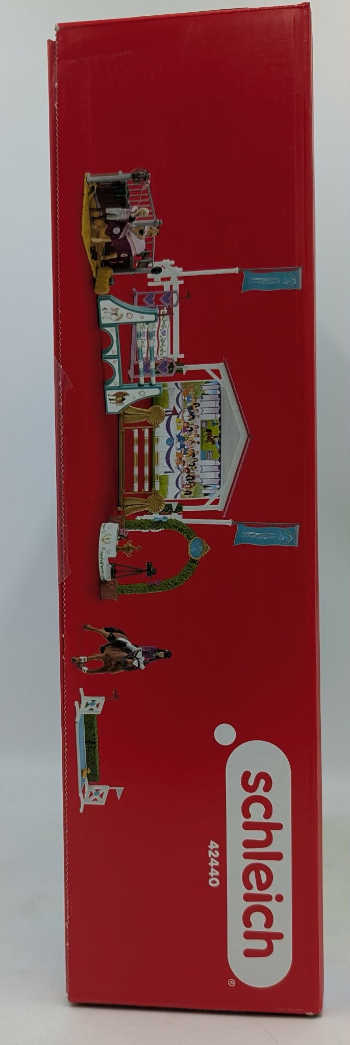 Schlechte Box mit Pferde- und Reiterfiguren, Hindernissen und Fahnen.
