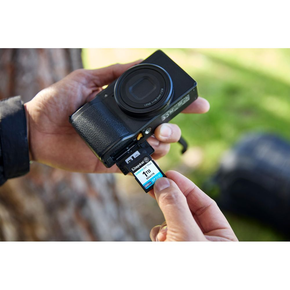 A hand inserts a 1TB SD card into a black camera.