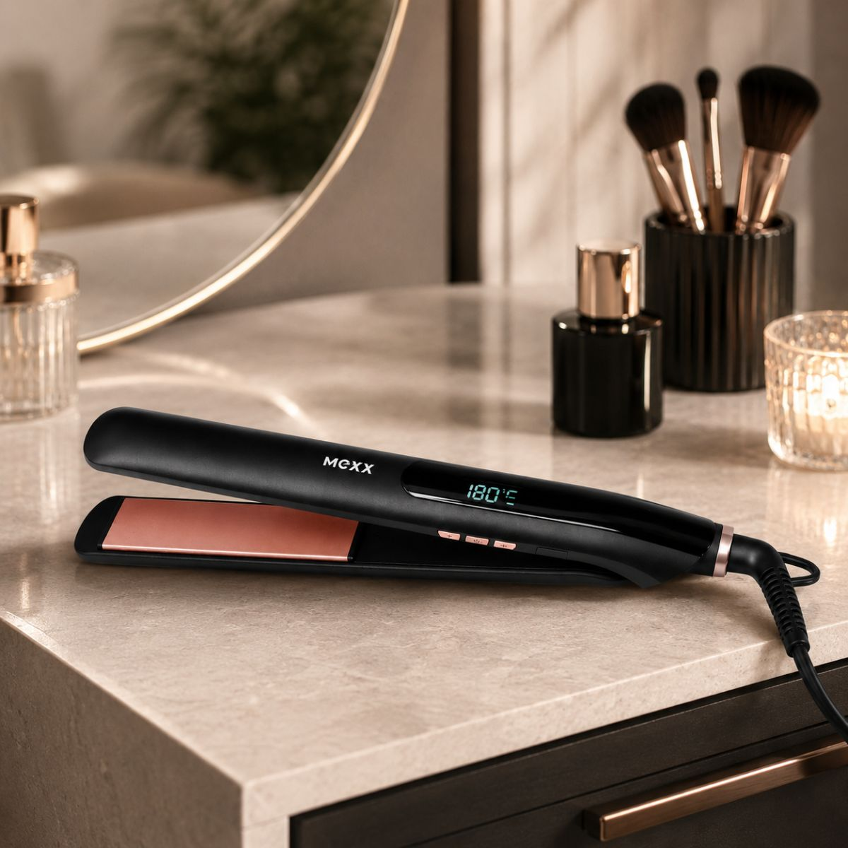 A black hair straightener with rose gold plates rests on a countertop.