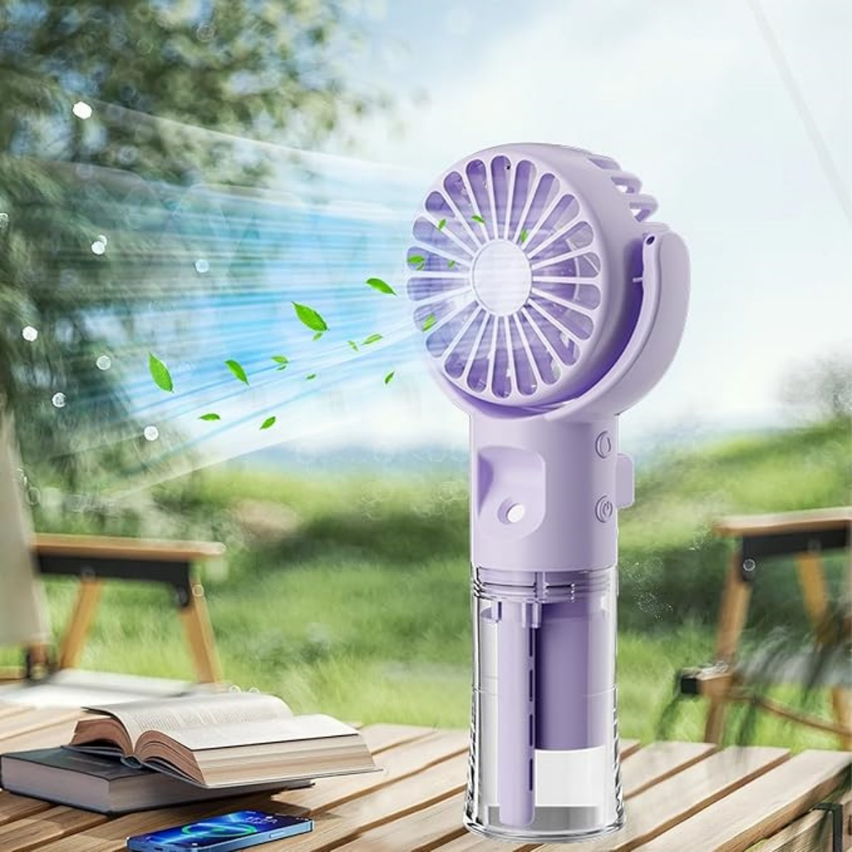 Ein violetter Handventilator mit Blättern, die aus einem Buch und Handy auf einem Holztisch wehen.