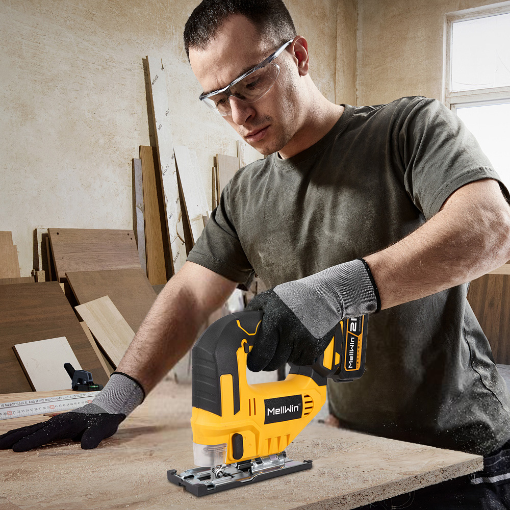 Mann mit Schutzbrille und Handschuhen sägt Holz mit einem gelben Stichsäge.