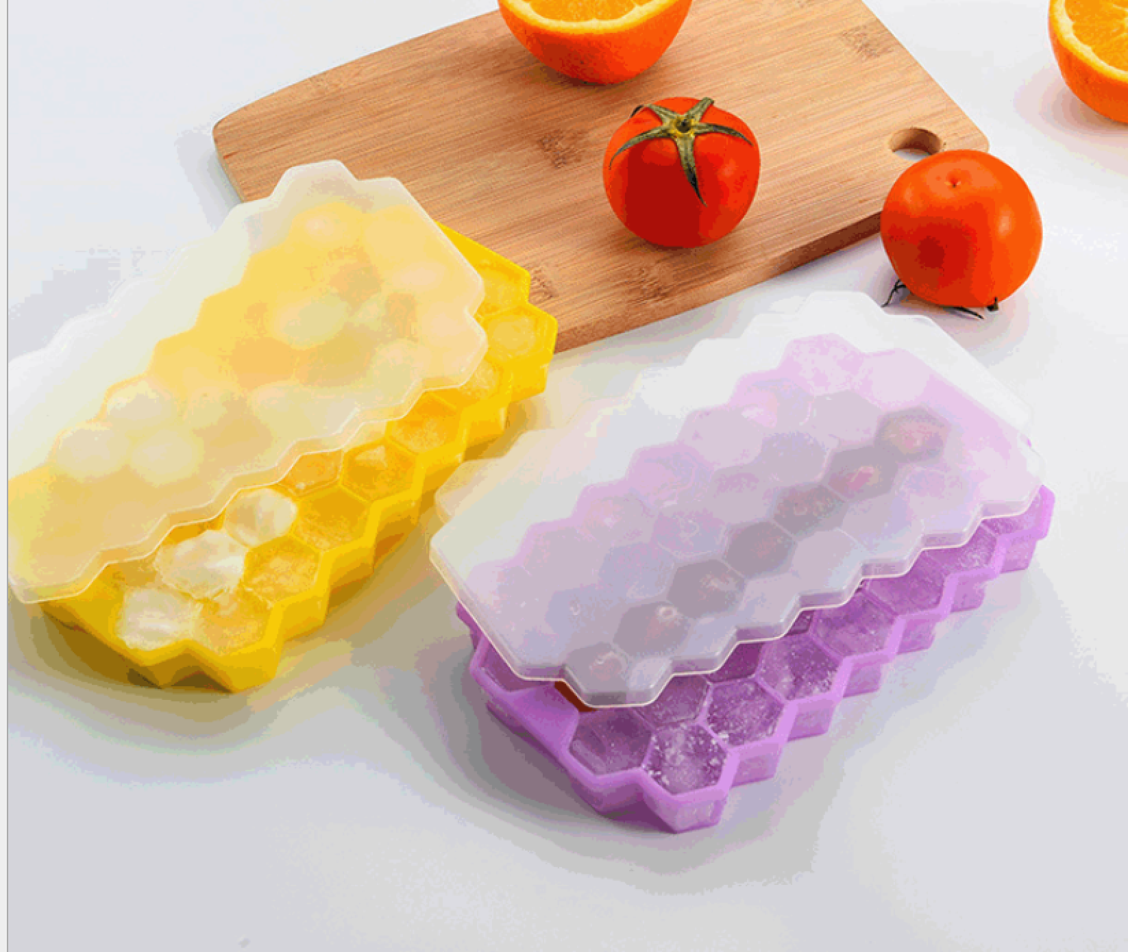 Zwei sechseckige Eiswürfelformen, eine gelb, eine lila, mit Eiswürfeln gefüllt.