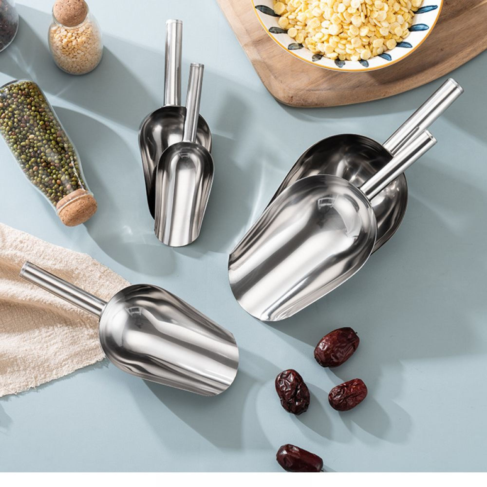 Metallschaufeln liegen neben Gläsern mit Lebensmitteln und getrockneten Früchten.