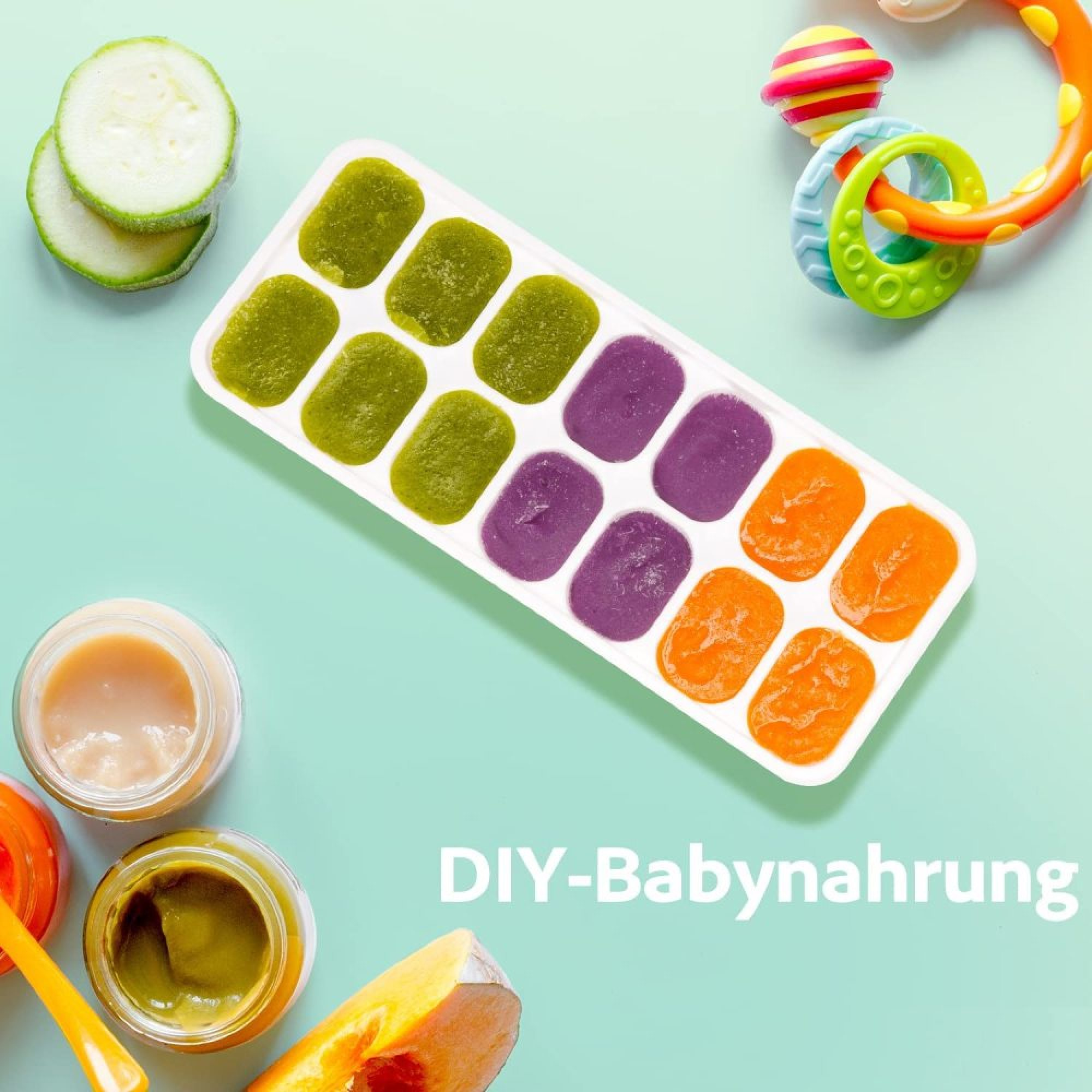 Eiswürfelform mit grüner, violetter und oranger Babynahrung, Zucchini, Gläschen und Spielzeug.