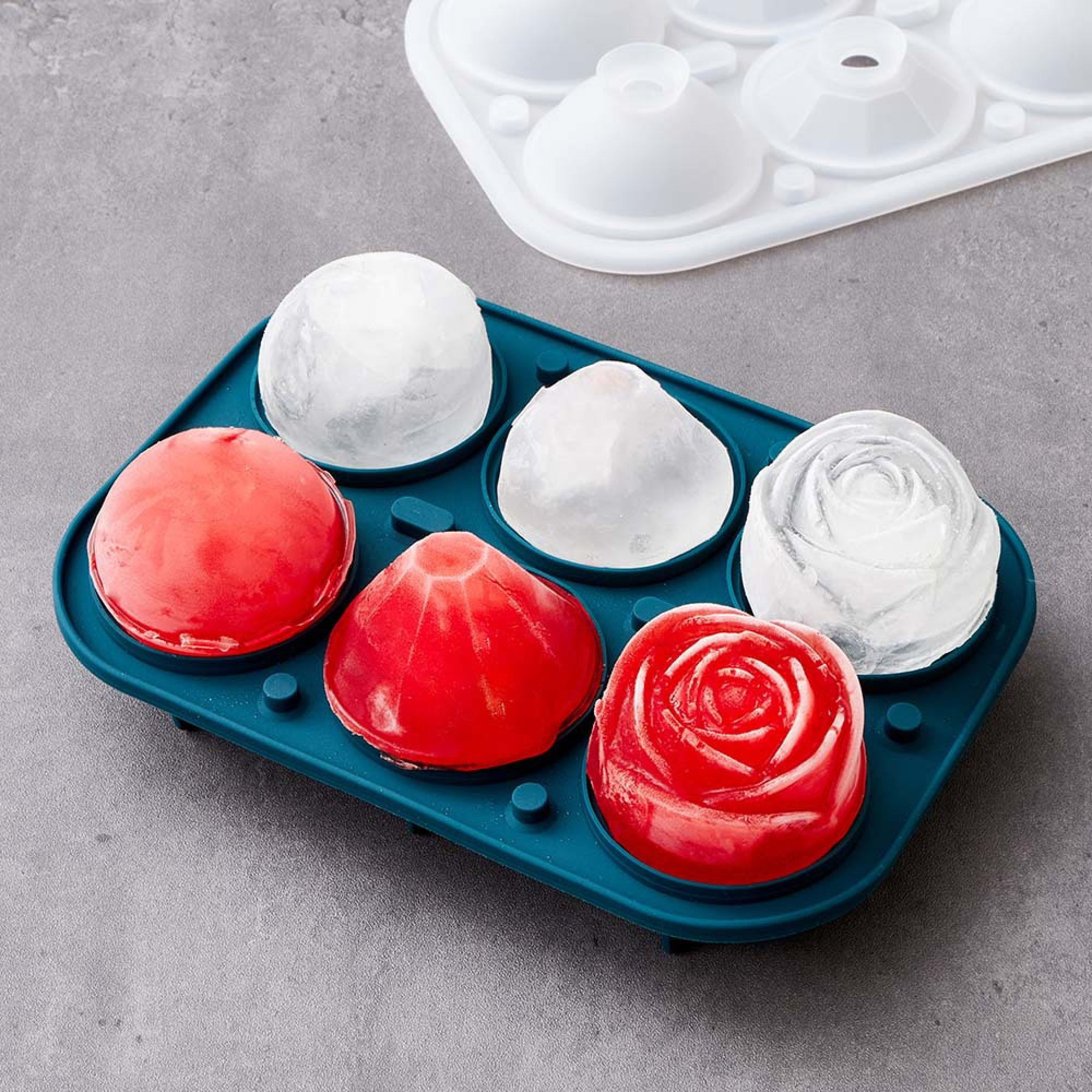 Ein blauer Eiswürfelbehälter mit verschiedenen Eisformen: Kugeln, Rosen und Kegel.