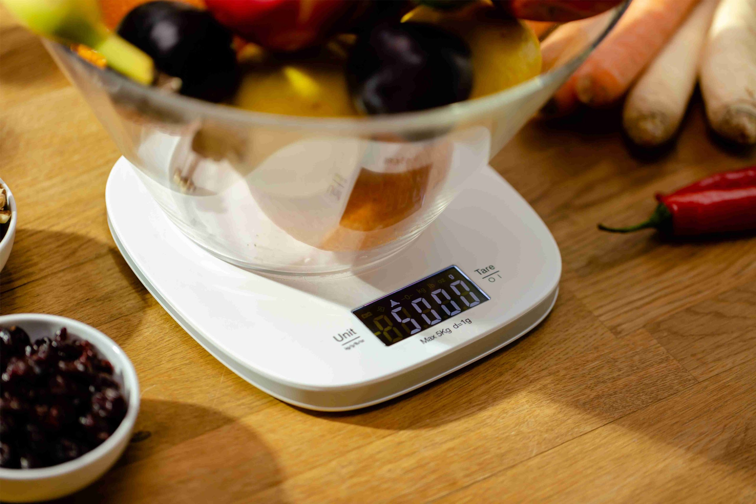 Eine digitale Küchenwaage zeigt 850,00g an. Daneben liegen Früchte und Gemüse.