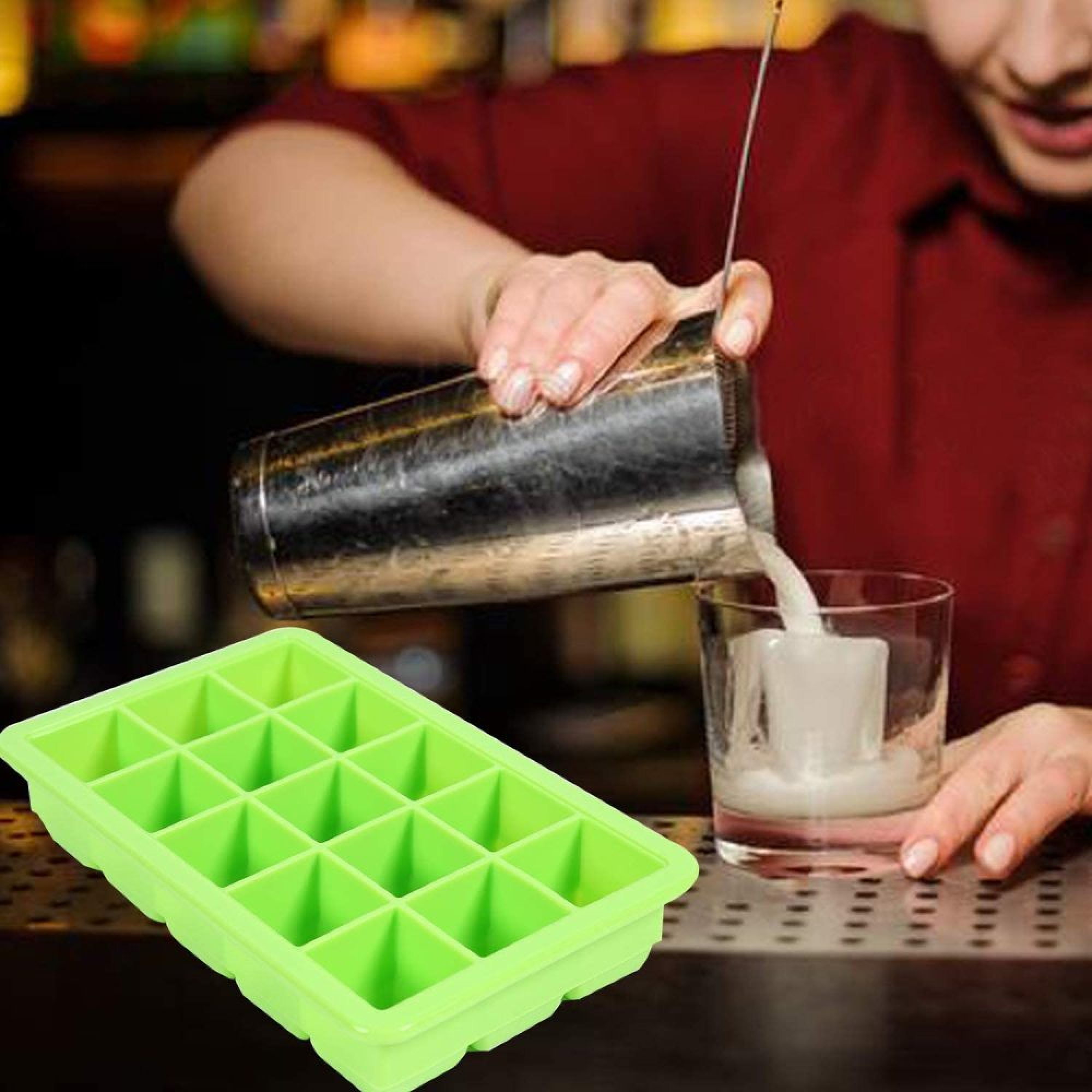 Ein Barkeeper gießt aus einem Shaker in ein Glas, daneben eine grüne Eiswürfelform.