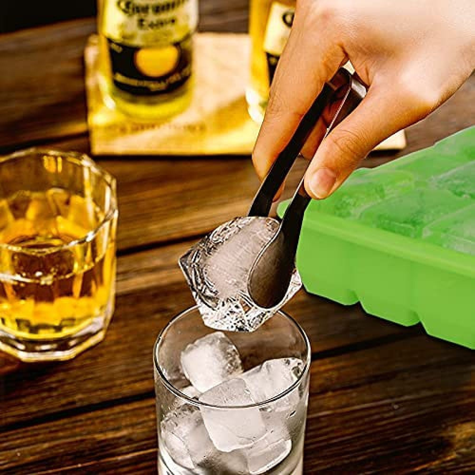 Eine Hand benutzt eine Zange, um Eis in ein Glas mit Alkohol zu geben.