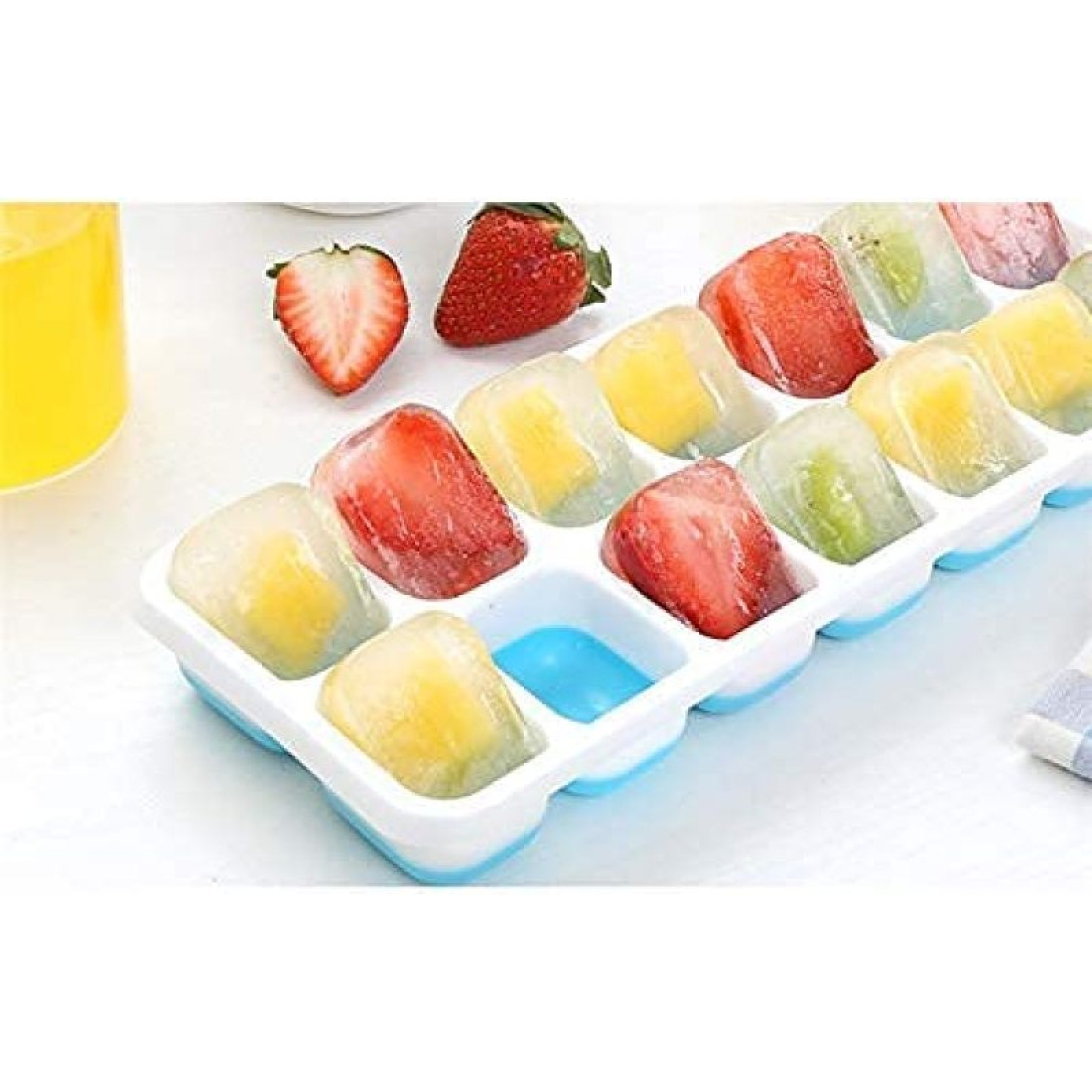 Eiswürfelform mit Früchten und einem Glas Saft.
