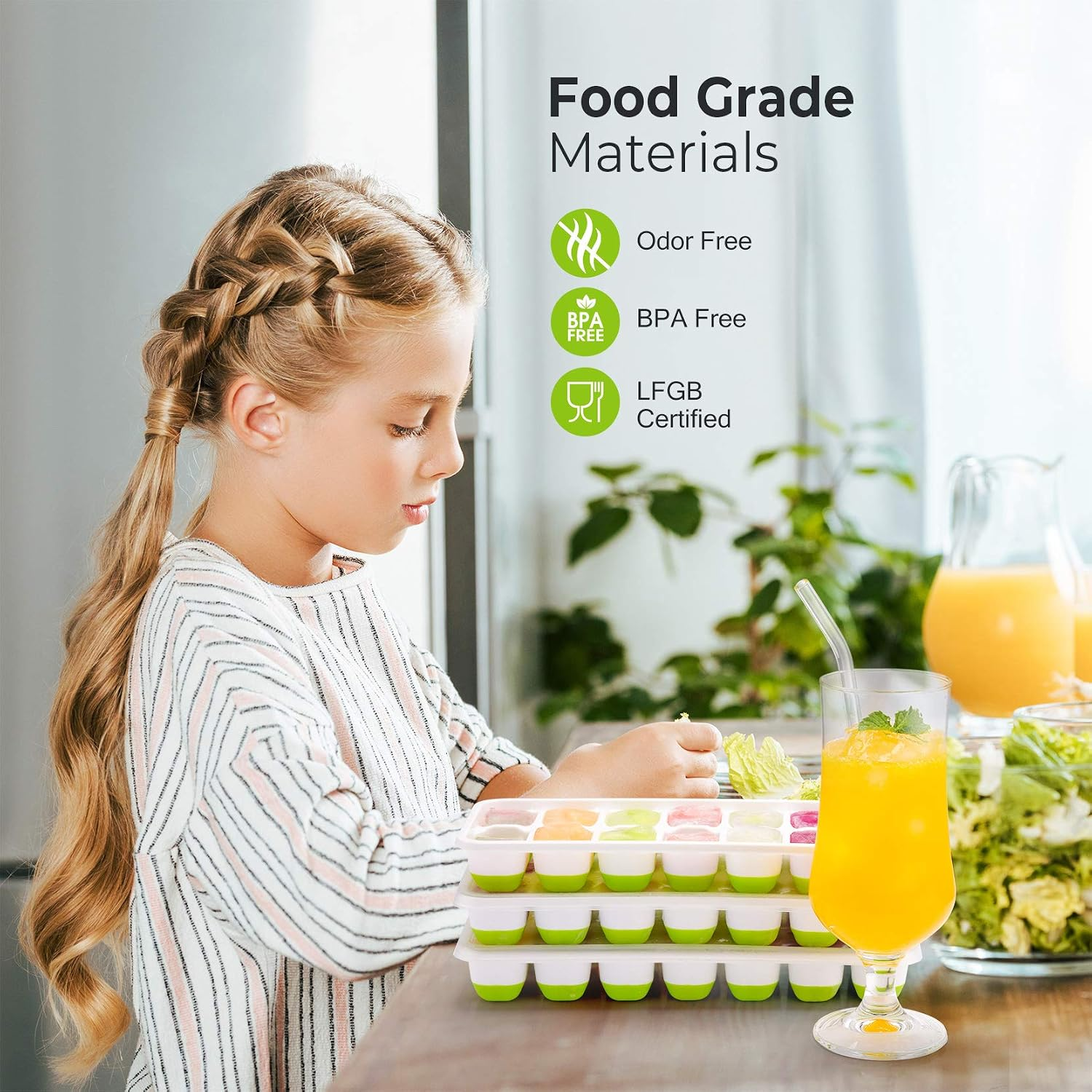 Ein Mädchen mit geflochtenen Haaren vor Eiswürfelformen, Saft und Salat.