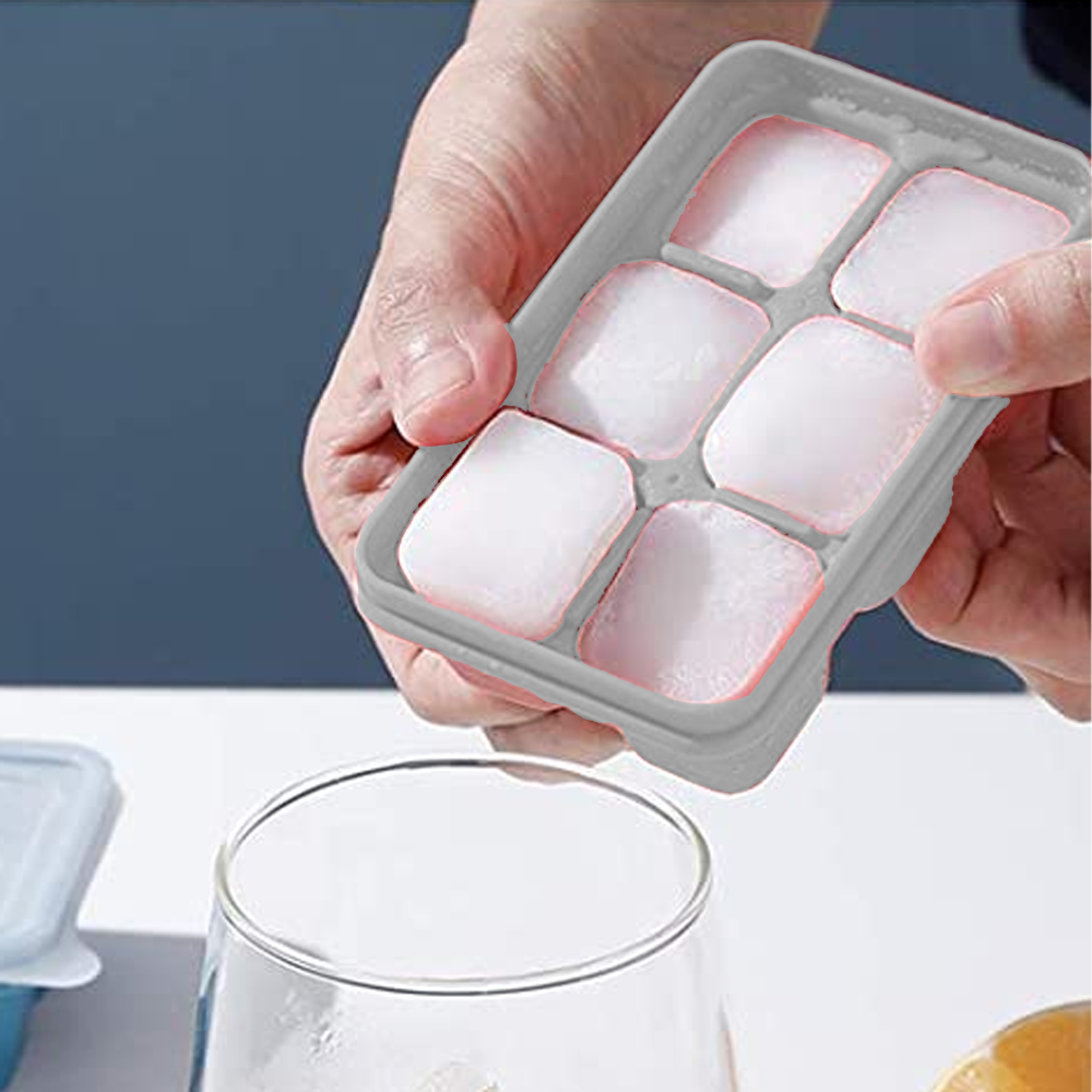 Eine Hand hält eine graue Eiswürfelform mit sechs Eiswürfeln über einem Glas.