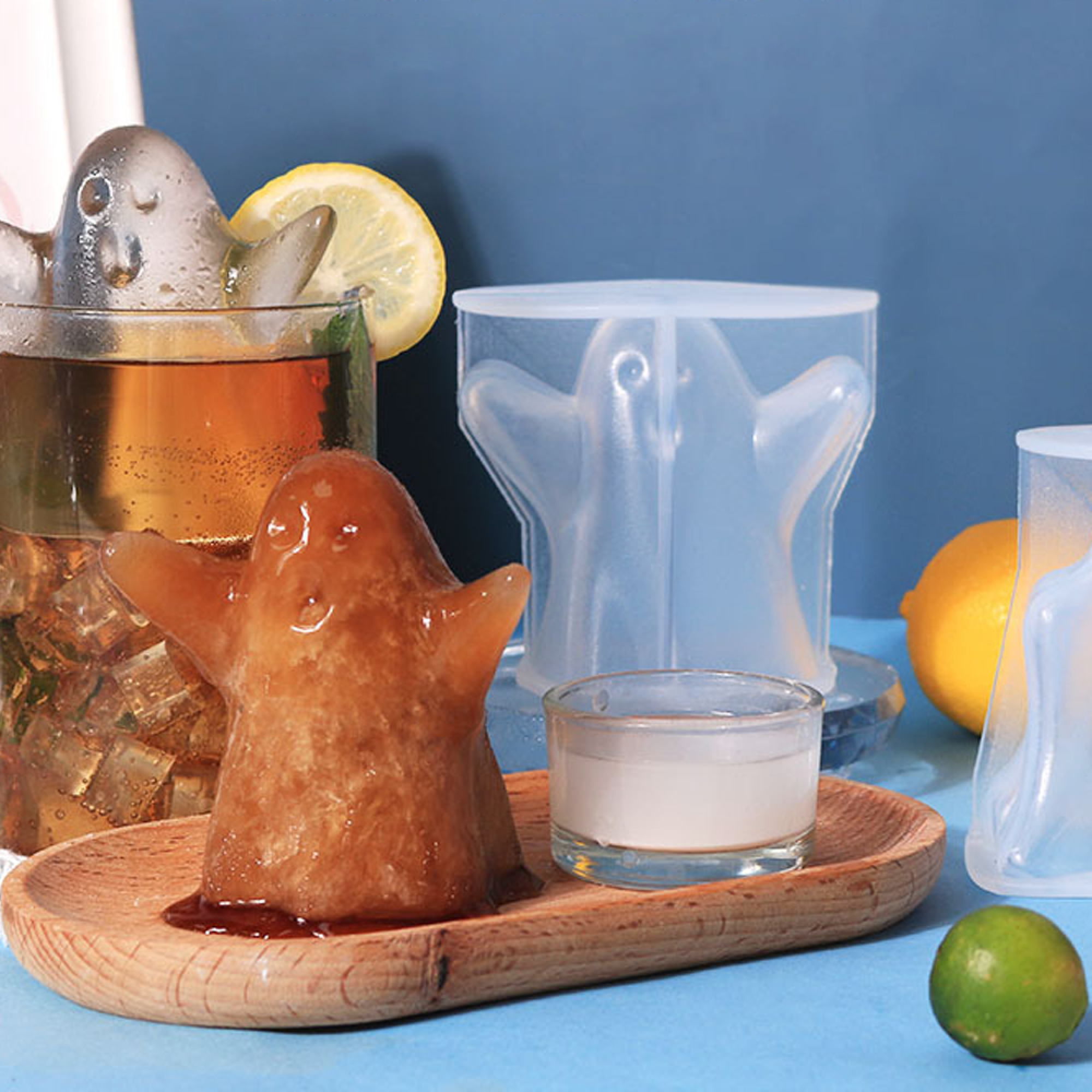 Geformtes Eis in Geisterform neben einem Glas mit Getränk und Zitrone.