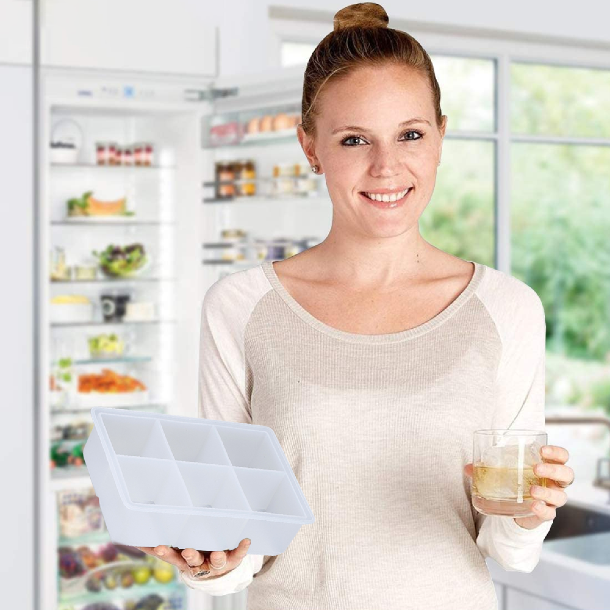 Eine Frau hält eine Eiswürfelform und ein Glas Whisky vor einem Kühlschrank.