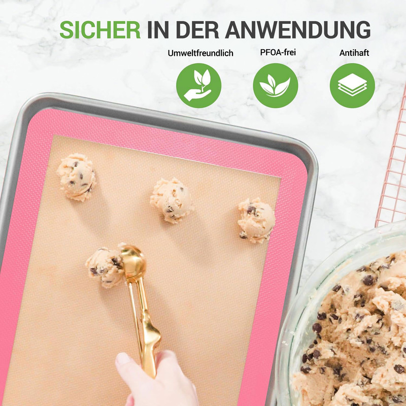 Ein Kochblech mit Keksteig, der auf einer Silikonmatte liegt. Ein Löffel gibt Teig hinzu.
