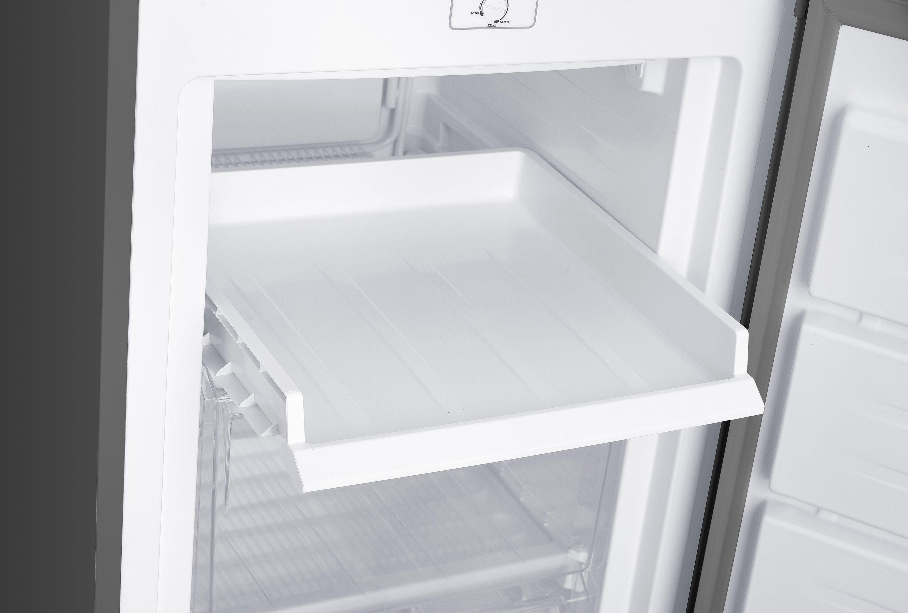 Ein weißer Kühlschrank mit ausziehbarer Schublade und Regalen.