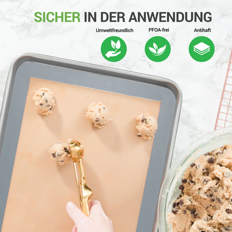 Keksteig wird mit einem Löffel auf ein Backblech mit Backmatte gegeben.