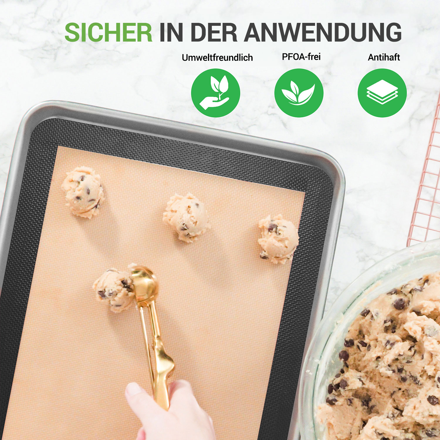 Ein Löffel gibt Teig auf eine Backmatte. Daneben liegen Kekse und eine Schüssel mit Teig.