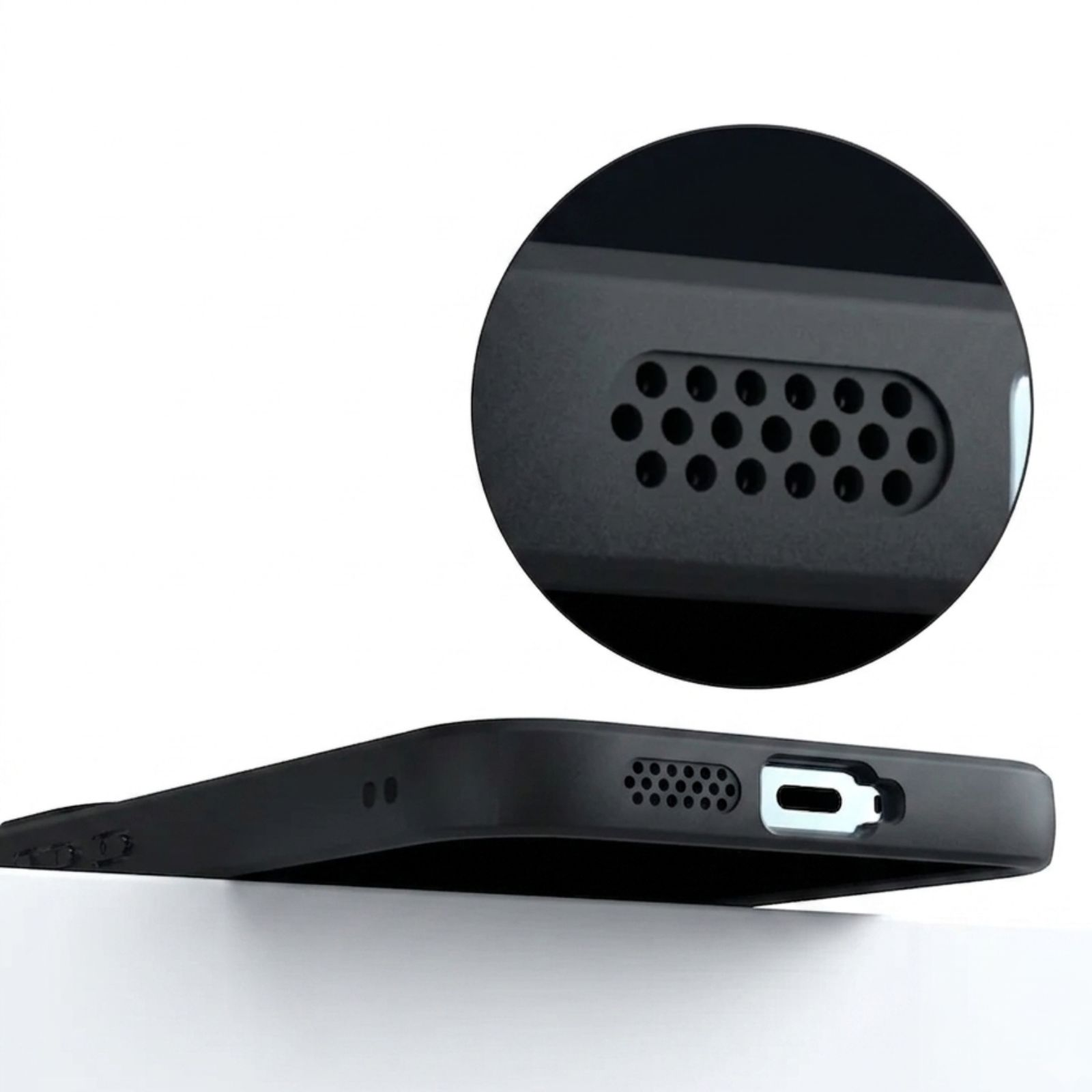 Primer plano de un puerto de carga de teléfono negro con perforaciones de altavoz.
