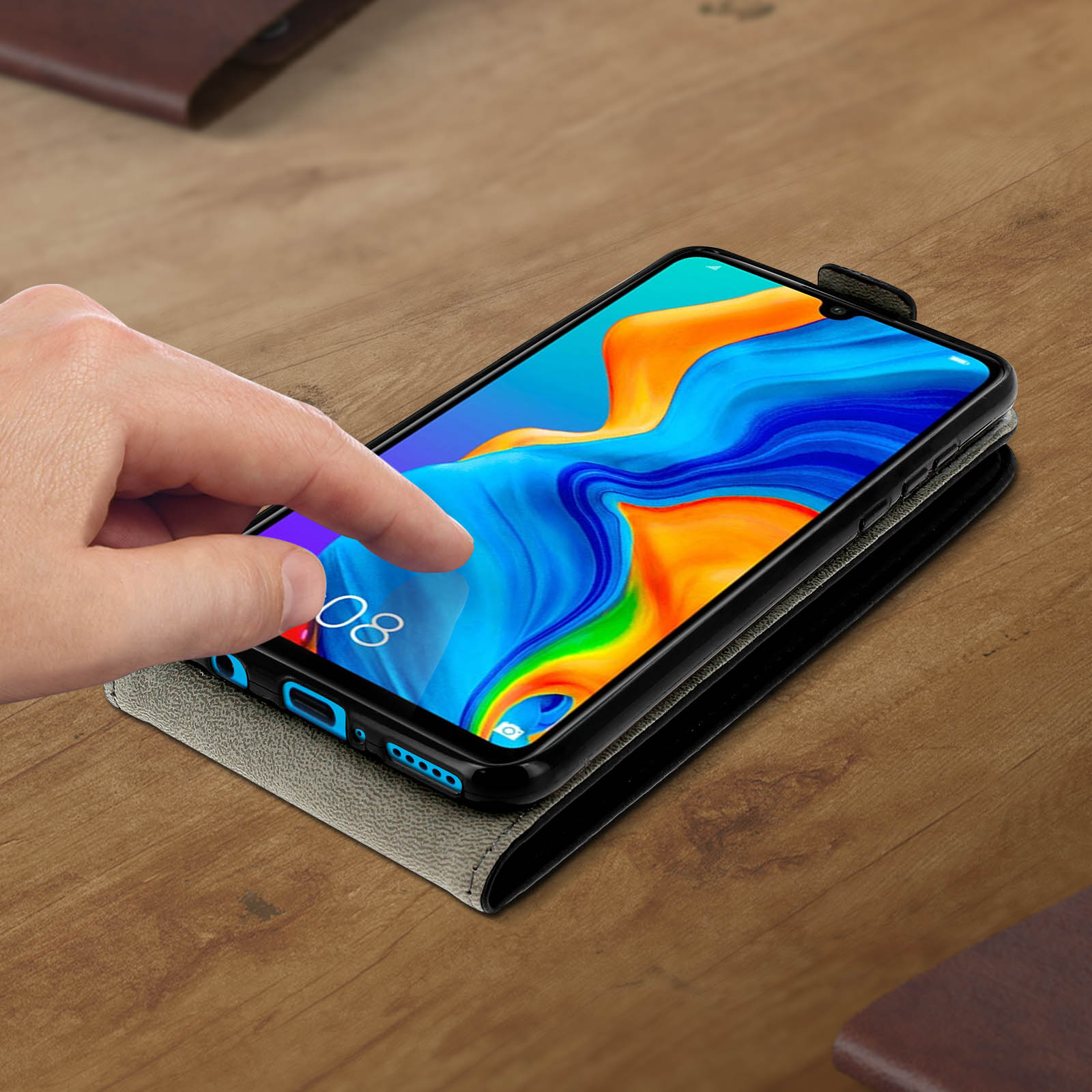 Una mano toca la pantalla de un smartphone con fondo de pantalla colorido en mesa de madera.