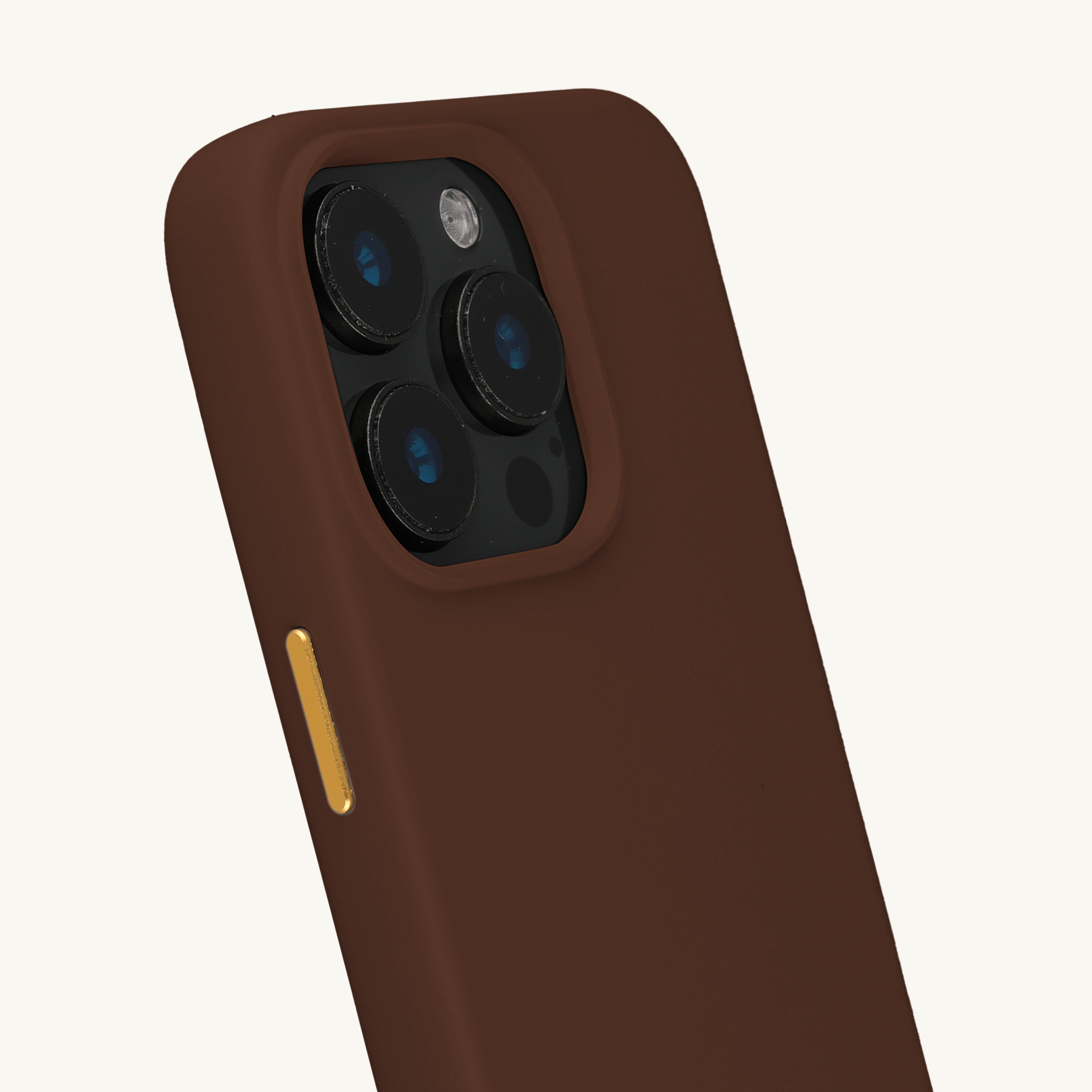 Gros plan d'une coque de téléphone marron montrant le module caméra et un bouton doré.