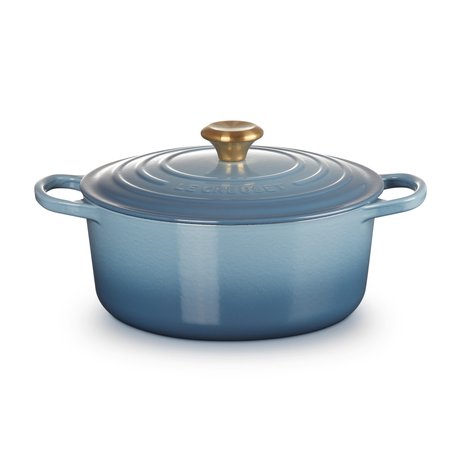 Poêle bleue avec bouton et anses dorés sur fond blanc.