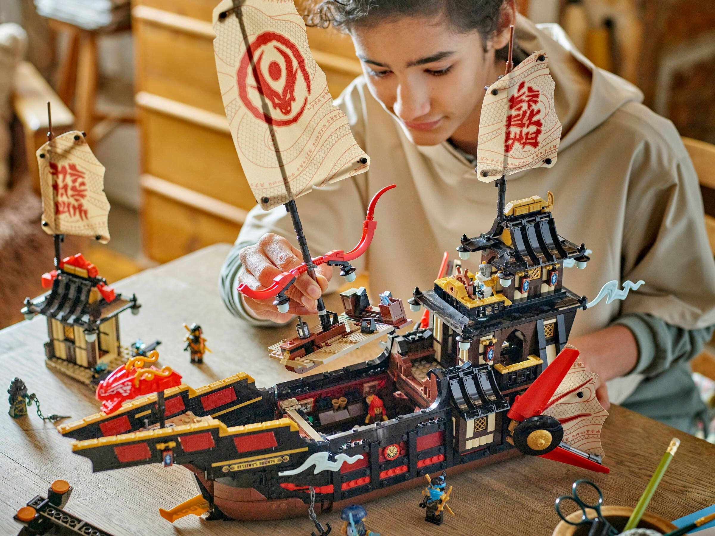 Ein Junge baut ein detailliertes Lego-Schiff mit Drachenmotiven, Figuren und Segeln.