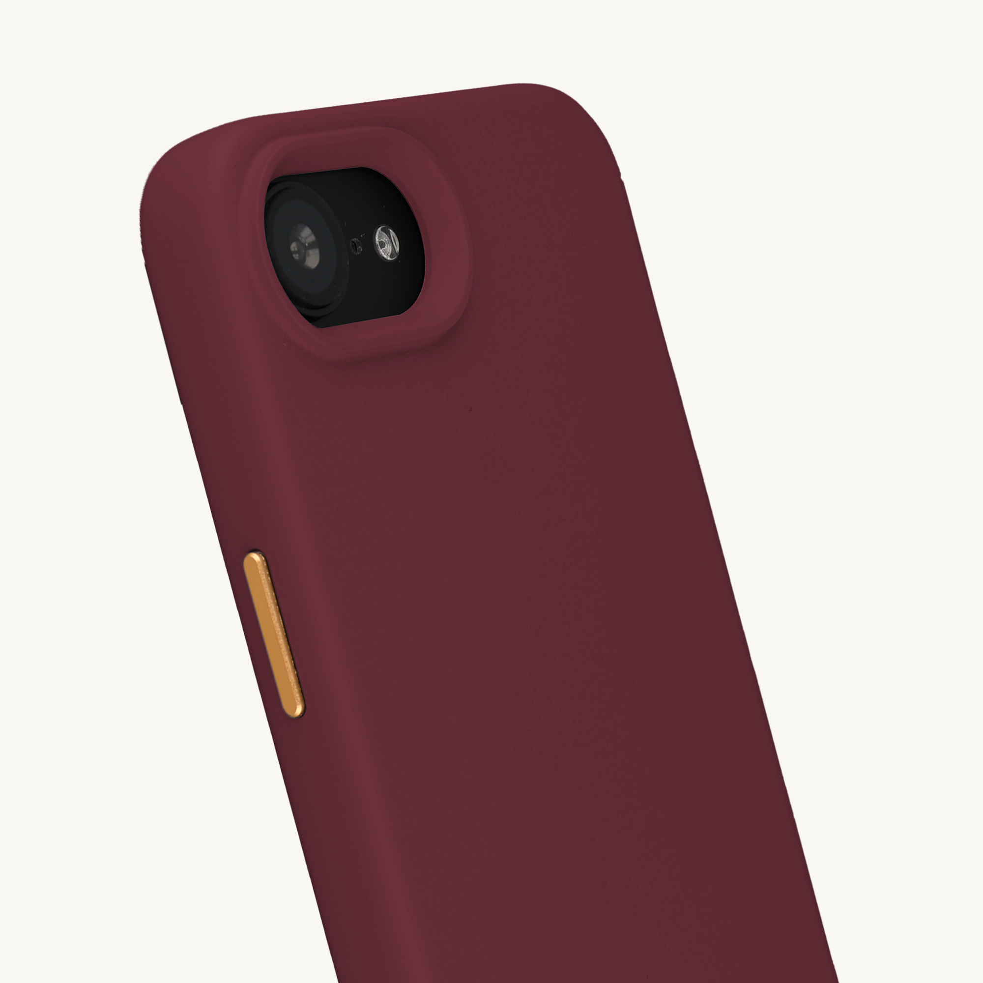 Gros plan d'une coque de téléphone bordeaux avec bouton doré et module caméra.