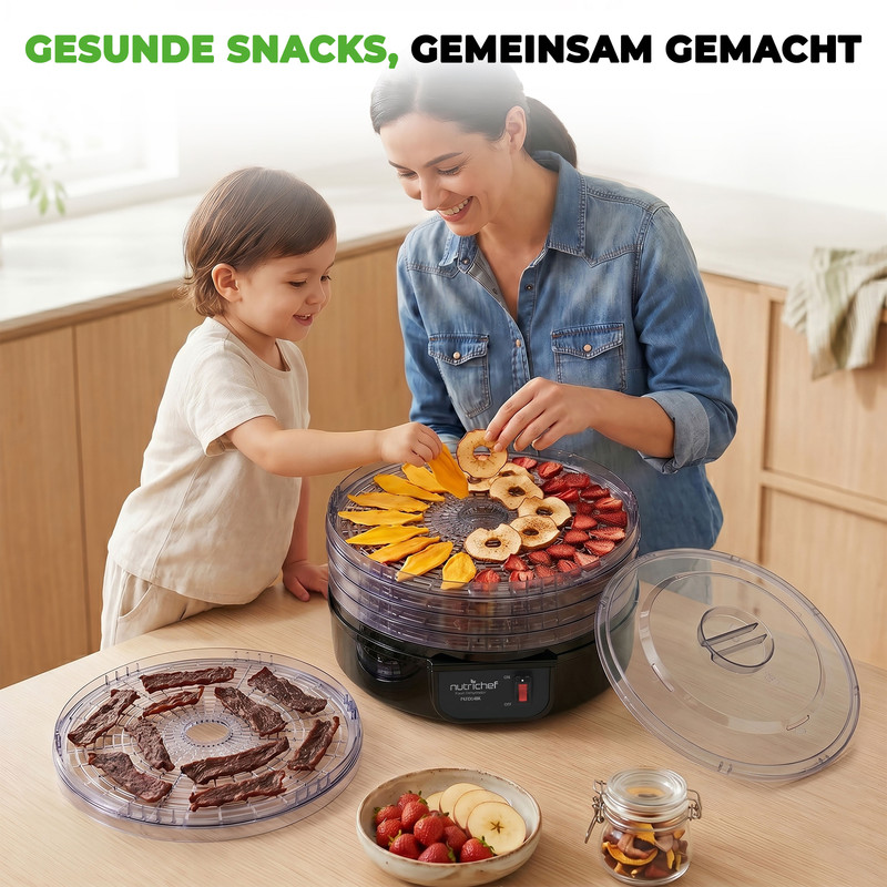 Mutter und Kind trocknen Obst in einem Dörrgerät.