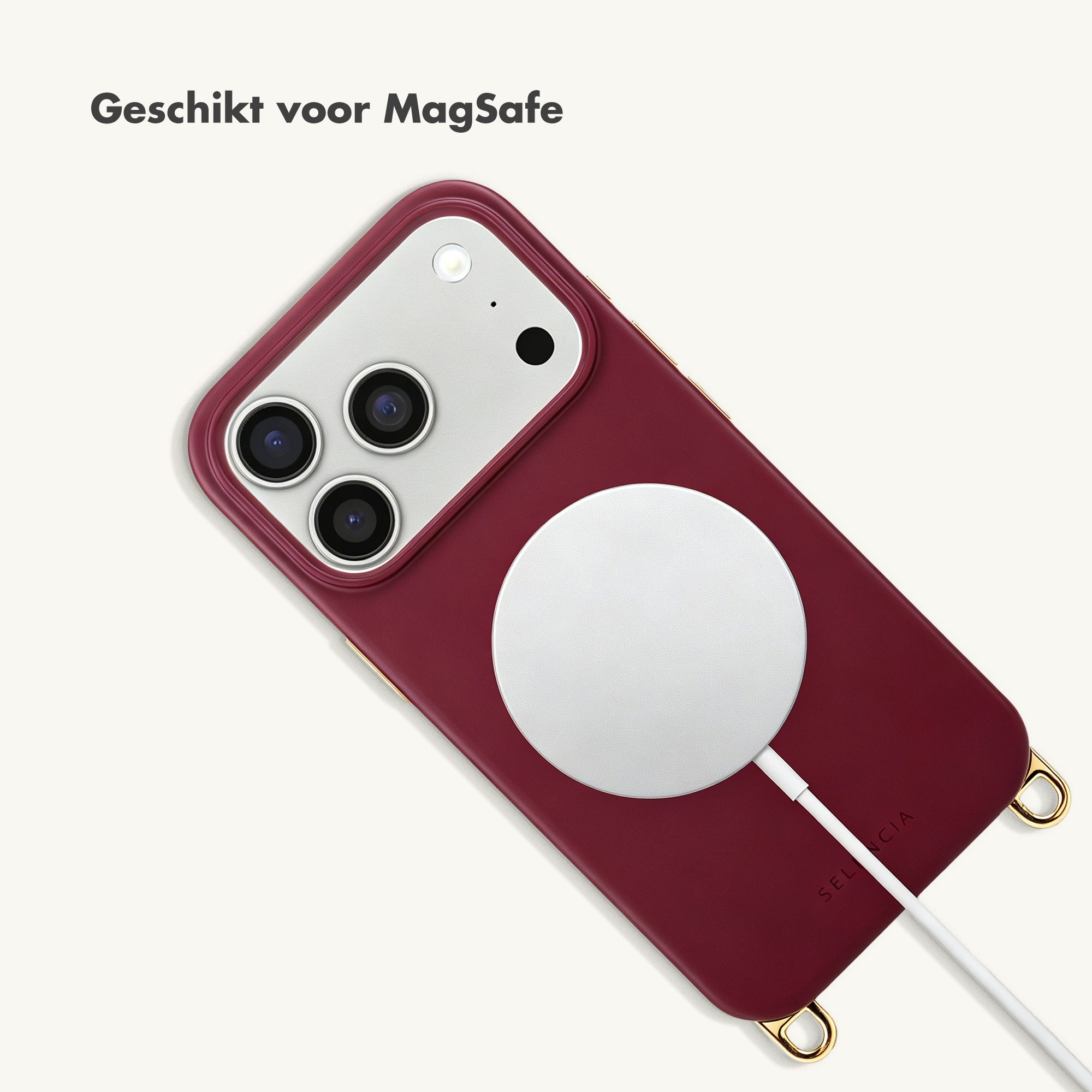 Een donkerrode iPhone met MagSafe lader en wit kabeltje.