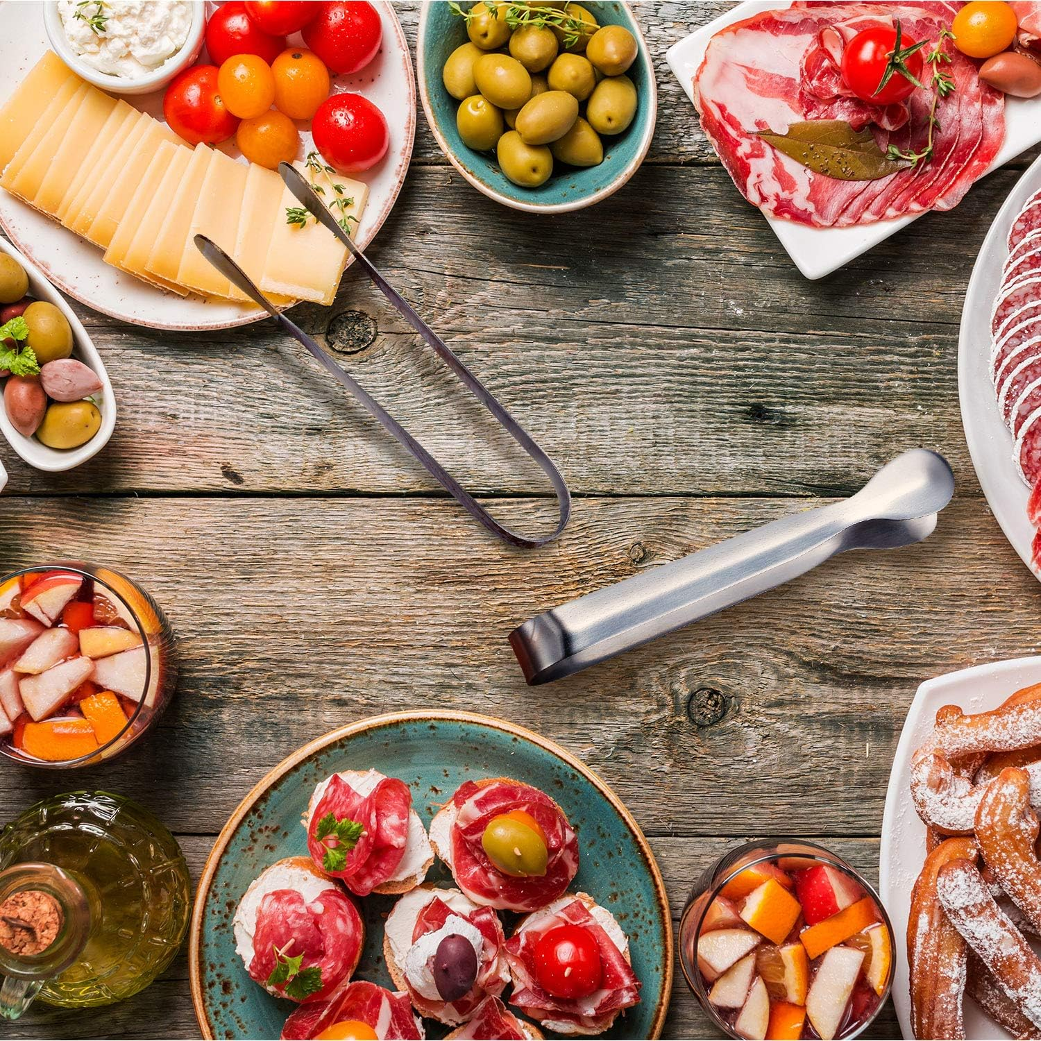 Holzoberfläche mit Käse, Oliven, Wurst, Obst, Churros und Getränken.