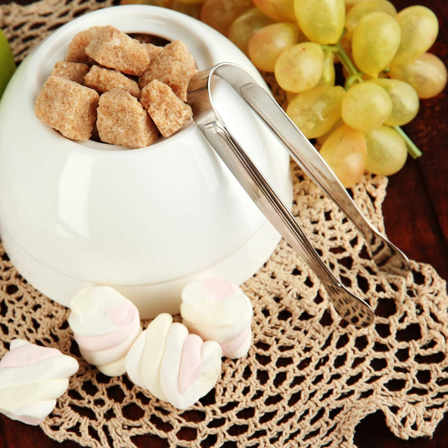 Brauner Zucker in einer Schale mit Marshmallows und Trauben daneben.