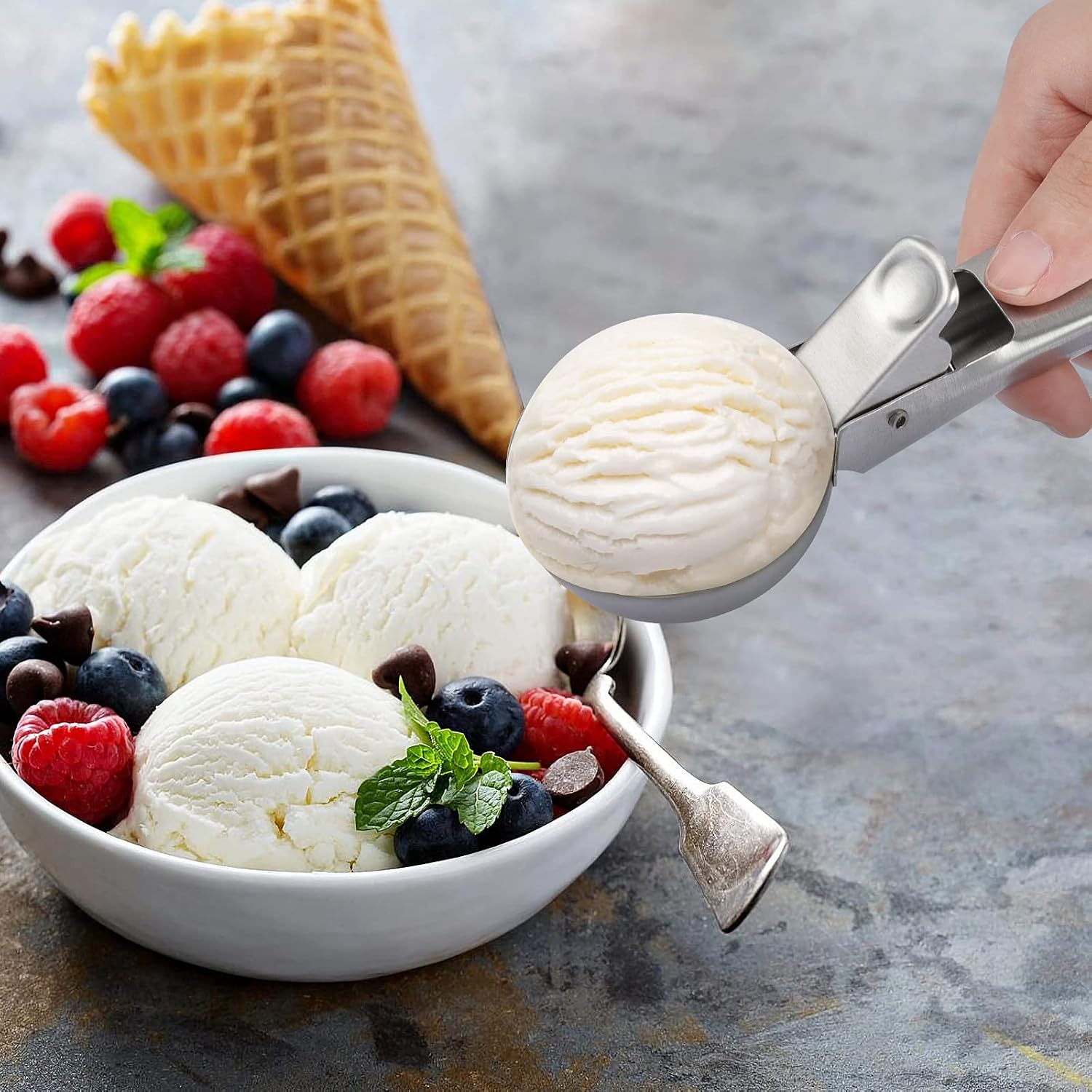 Eine Eisportion wird aus einer Schale mit Eiscreme, Beeren und Waffeln herausgenommen.