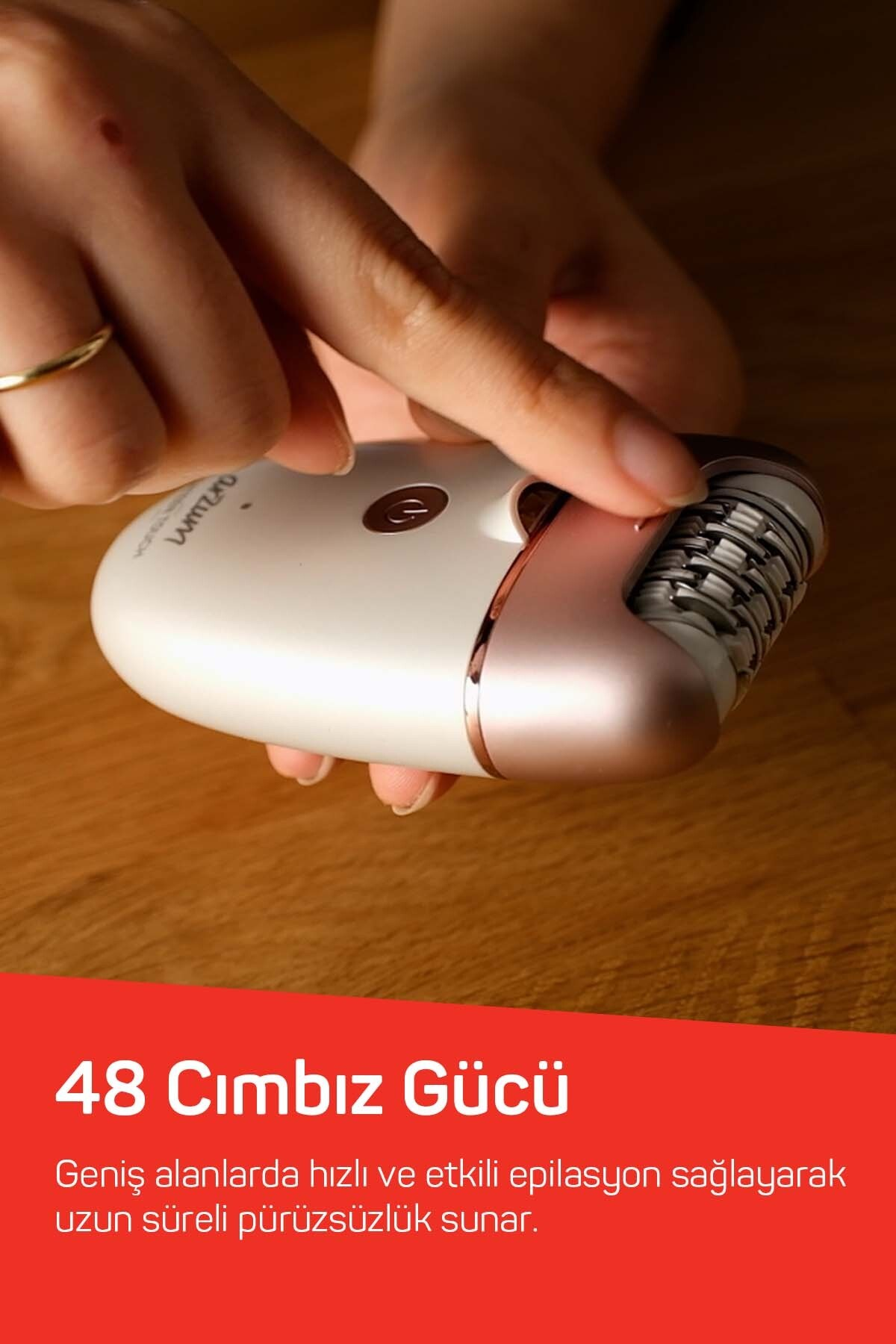 Bir el, rozet altın aksesuarlı ve rozet altın yüzüklü beyaz bir epilatör tutuyor.