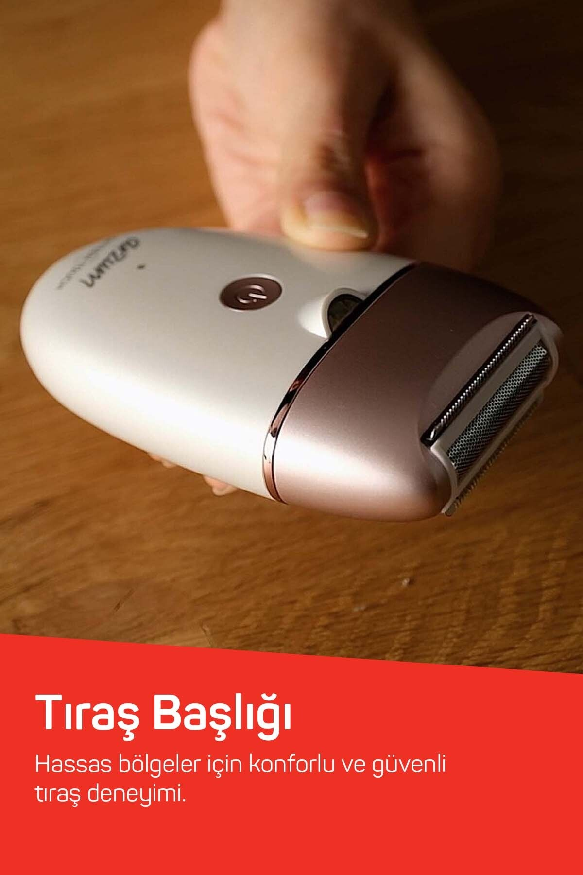 Ahşap zeminde tıraş başlığı olan beyaz ve rose gold epilatör tutan el.