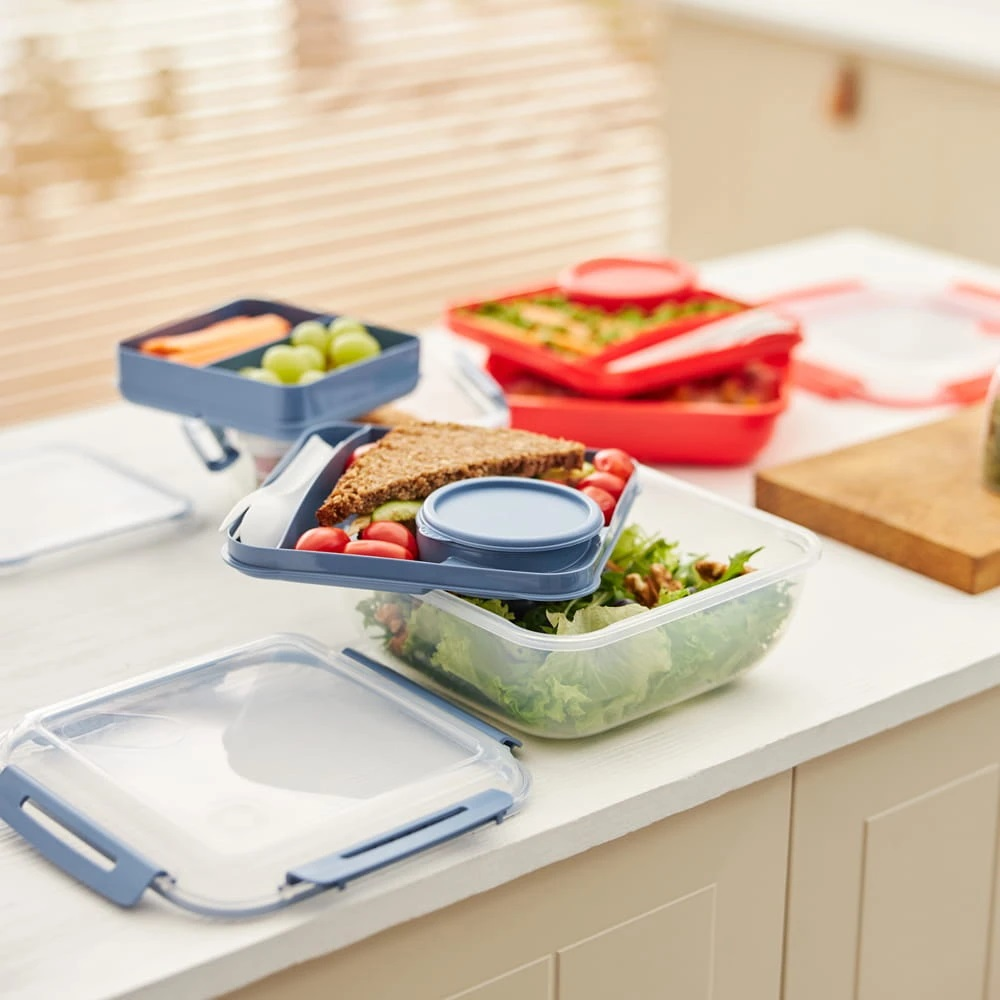 Kilka pudełek na lunch wypełnionych zdrową żywnością, taką jak sałatka i kanapki.