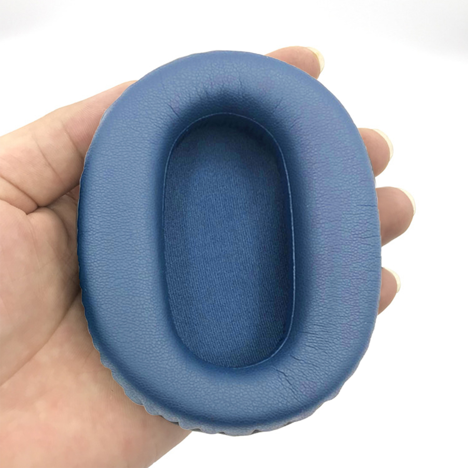 Eine Hand hält ein blaues Ohrpolster für Kopfhörer mit weißem Hintergrund.