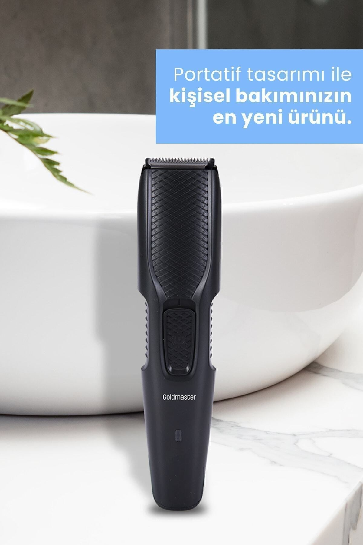 Siyah bir Goldmaster tıraş makinesi lavabonun yanındaki beyaz mermer yüzeyde duruyor.