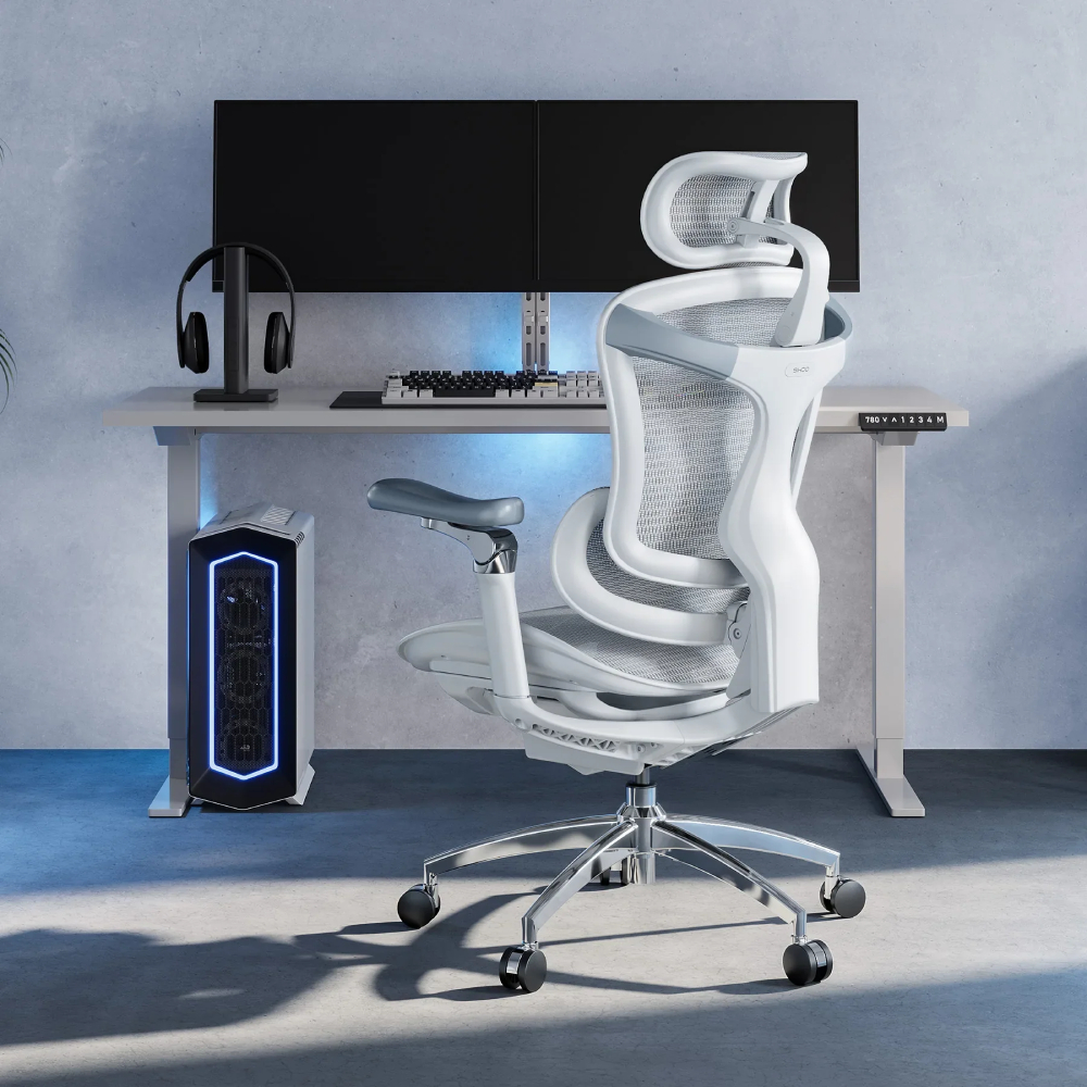 Ein weißer Bürostuhl steht vor einem Schreibtisch mit Computern und Kopfhörern.