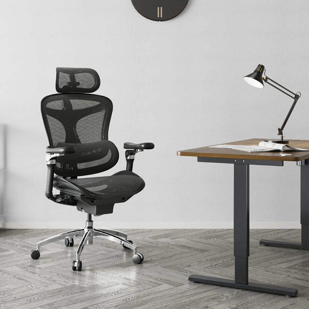 Ein schwarzer ergonomischer Bürostuhl steht auf einem Fischgrätparkettboden neben einem Schreibtisch.