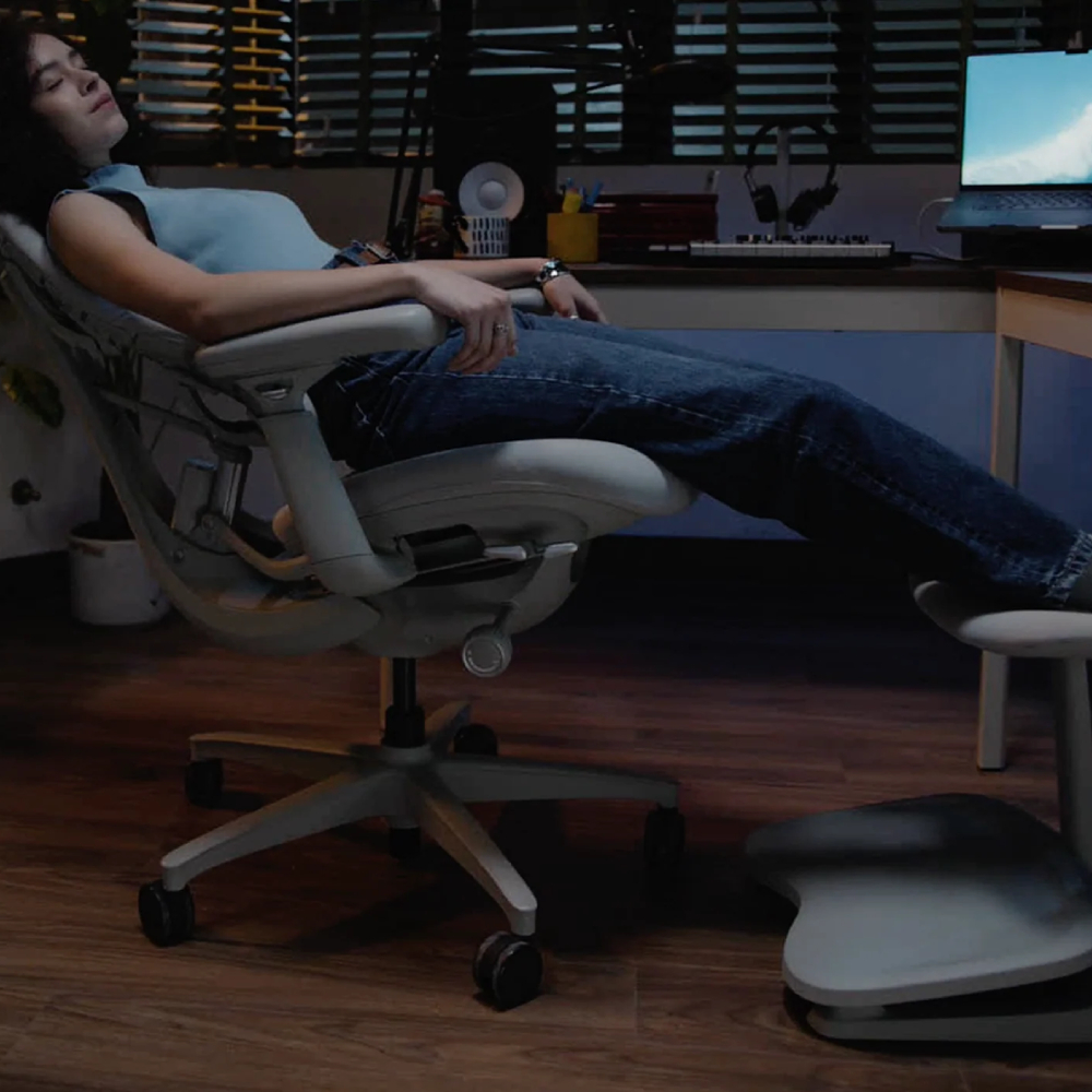 Una donna in jeans riposa su una sedia da ufficio ad occhi chiusi.