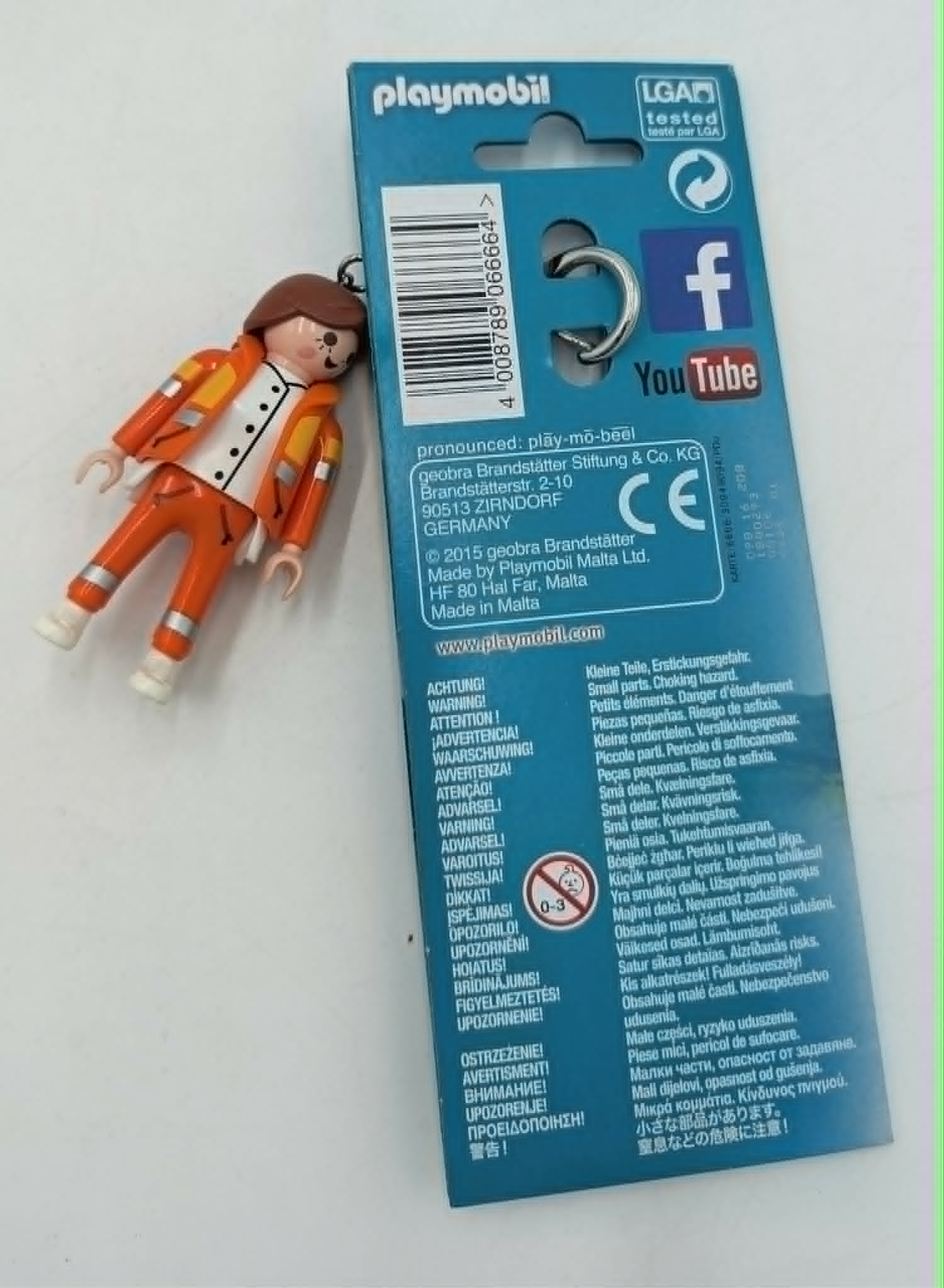 Personaggio Playmobil con tuta arancione, camicia bianca, capelli castani, su portachiavi.