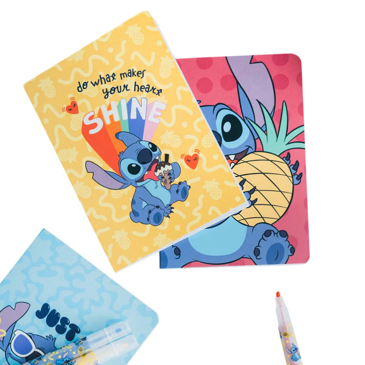 Drei Notizbücher im Stitch-Design und ein Stift. Gelbe, pinke und blaue Einbände mit Stitch-Grafiken und Text.