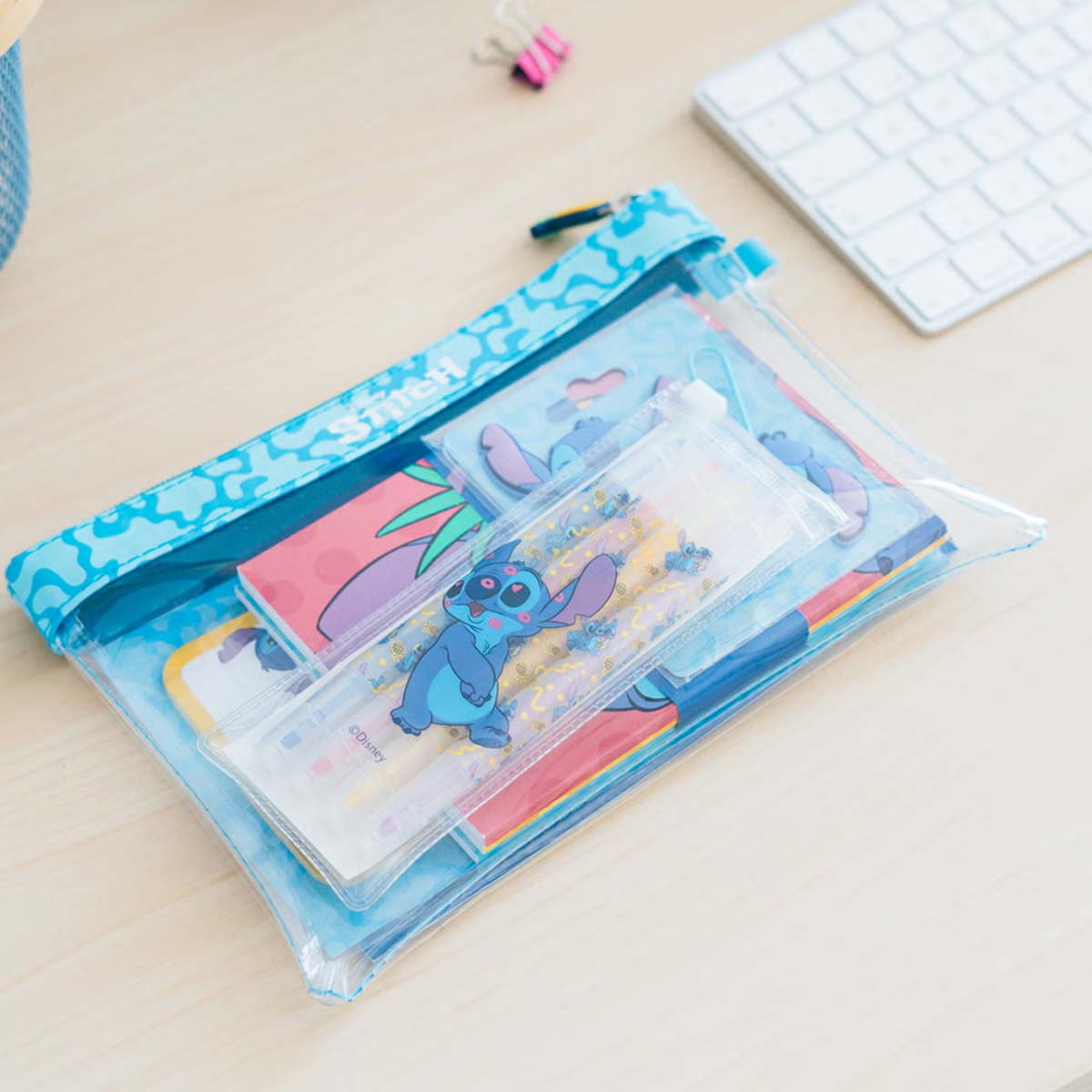 Eine durchsichtige Tasche mit Stitch-Motiv, gefüllt mit Schreibwaren wie Notizbüchern und Stiften.