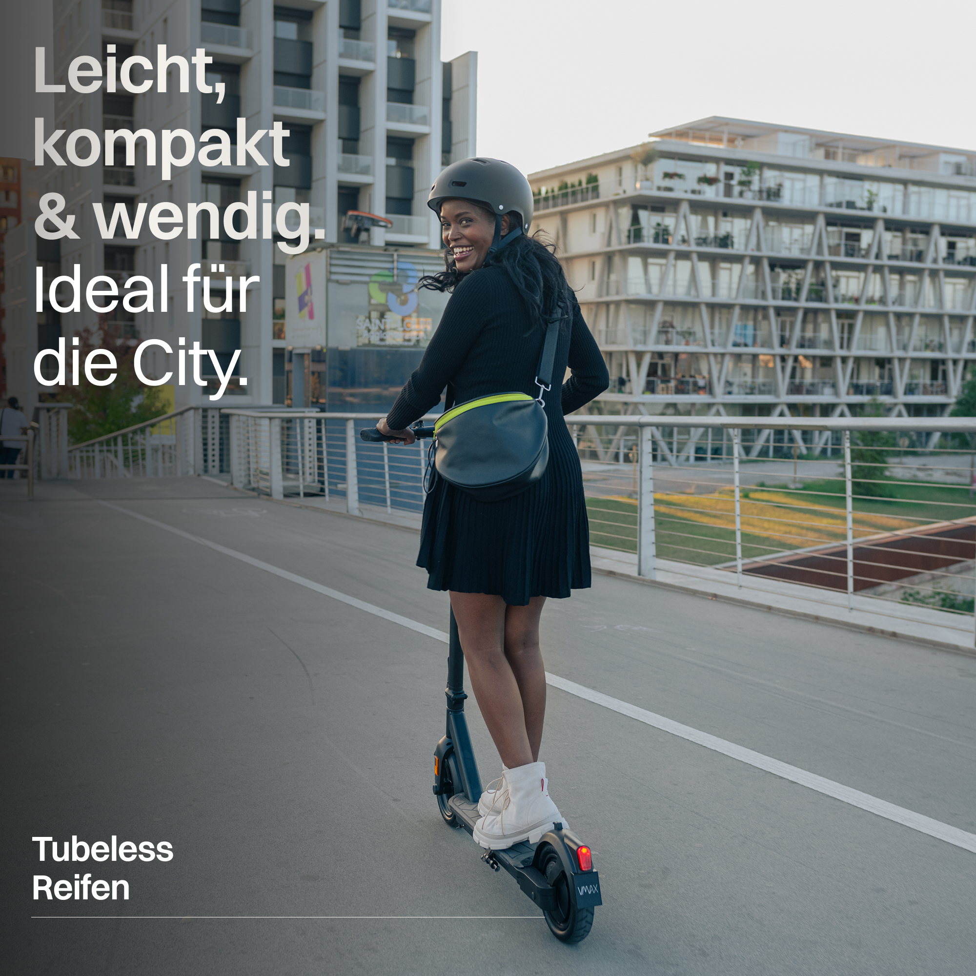 Femme avec casque conduit un scooter électrique sur un pont, bâtiments modernes.