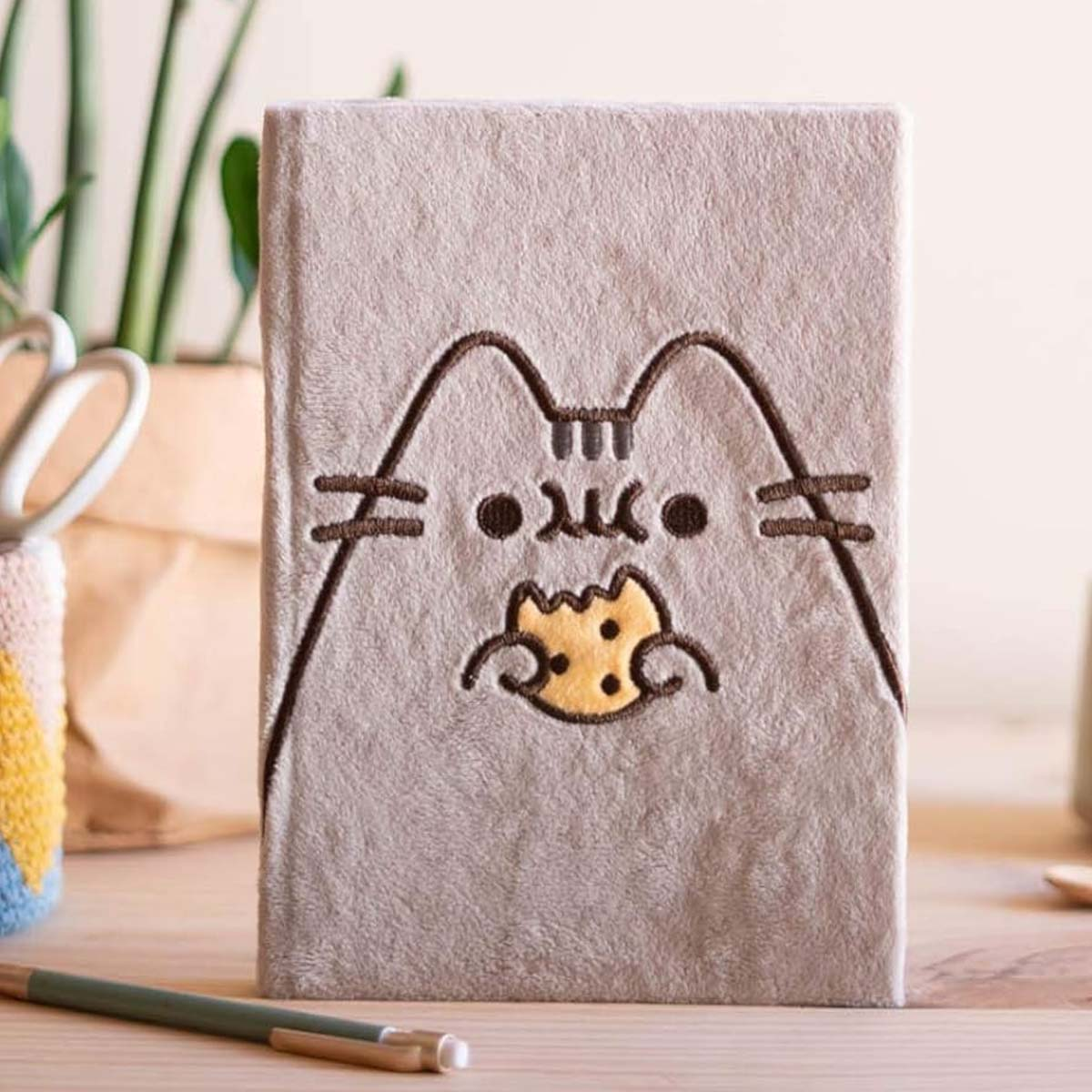 Plüsch-Notizbuch mit aufgestickter Pusheen-Katze, die einen Keks isst.