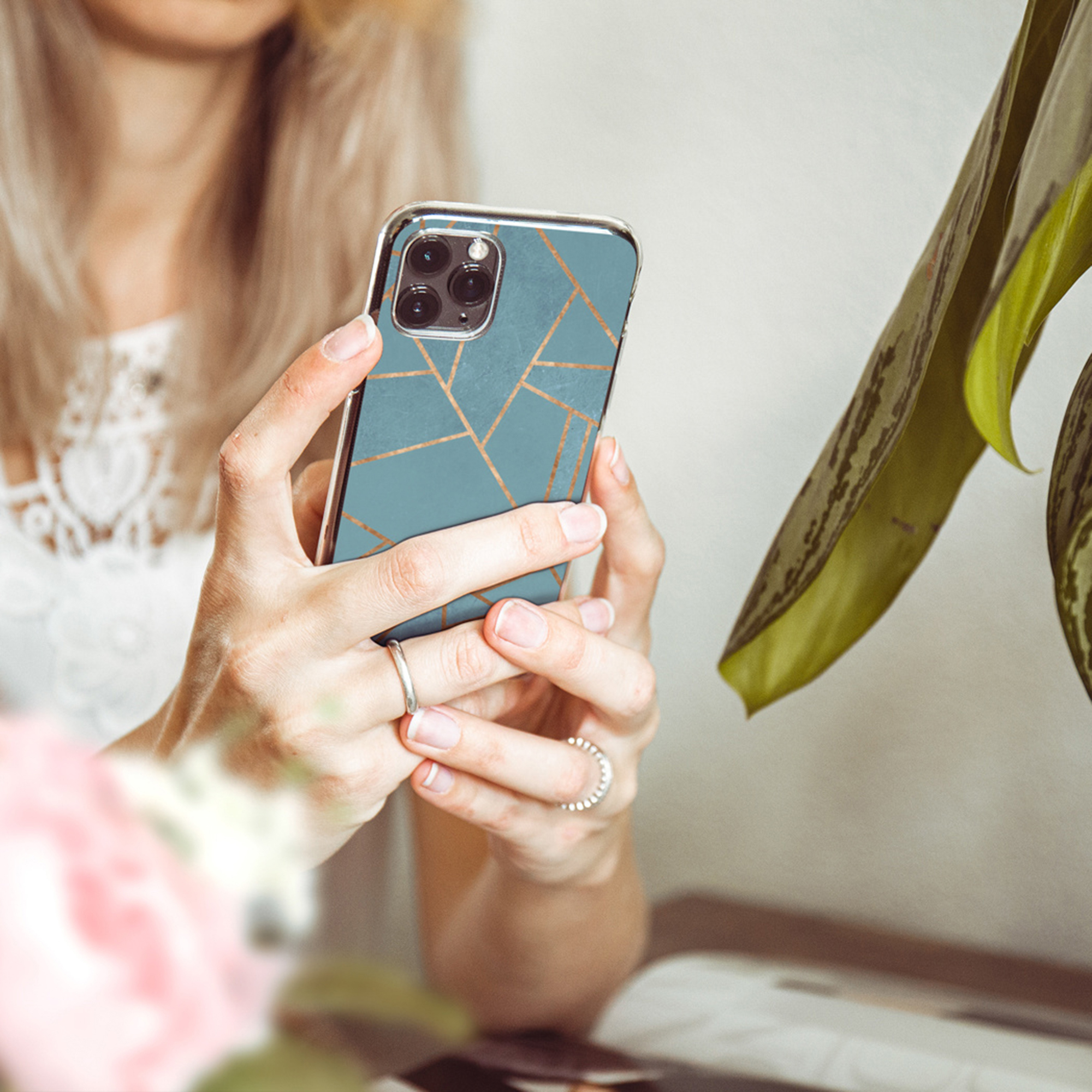 Una persona tiene uno smartphone con motivo blu e linee dorate.