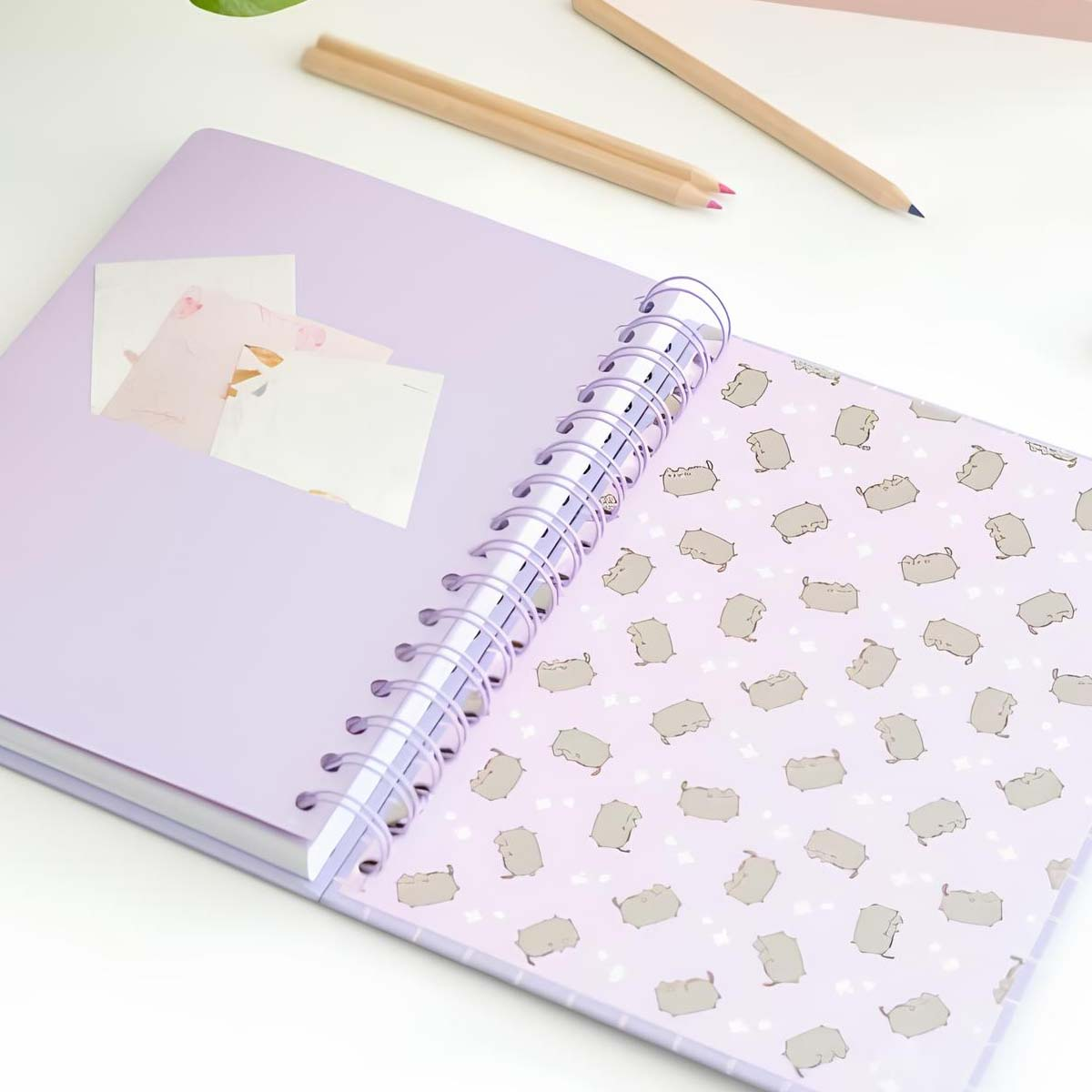 Lila Notizbuch mit Katzenmuster, zwei Bleistiften und Notizen.